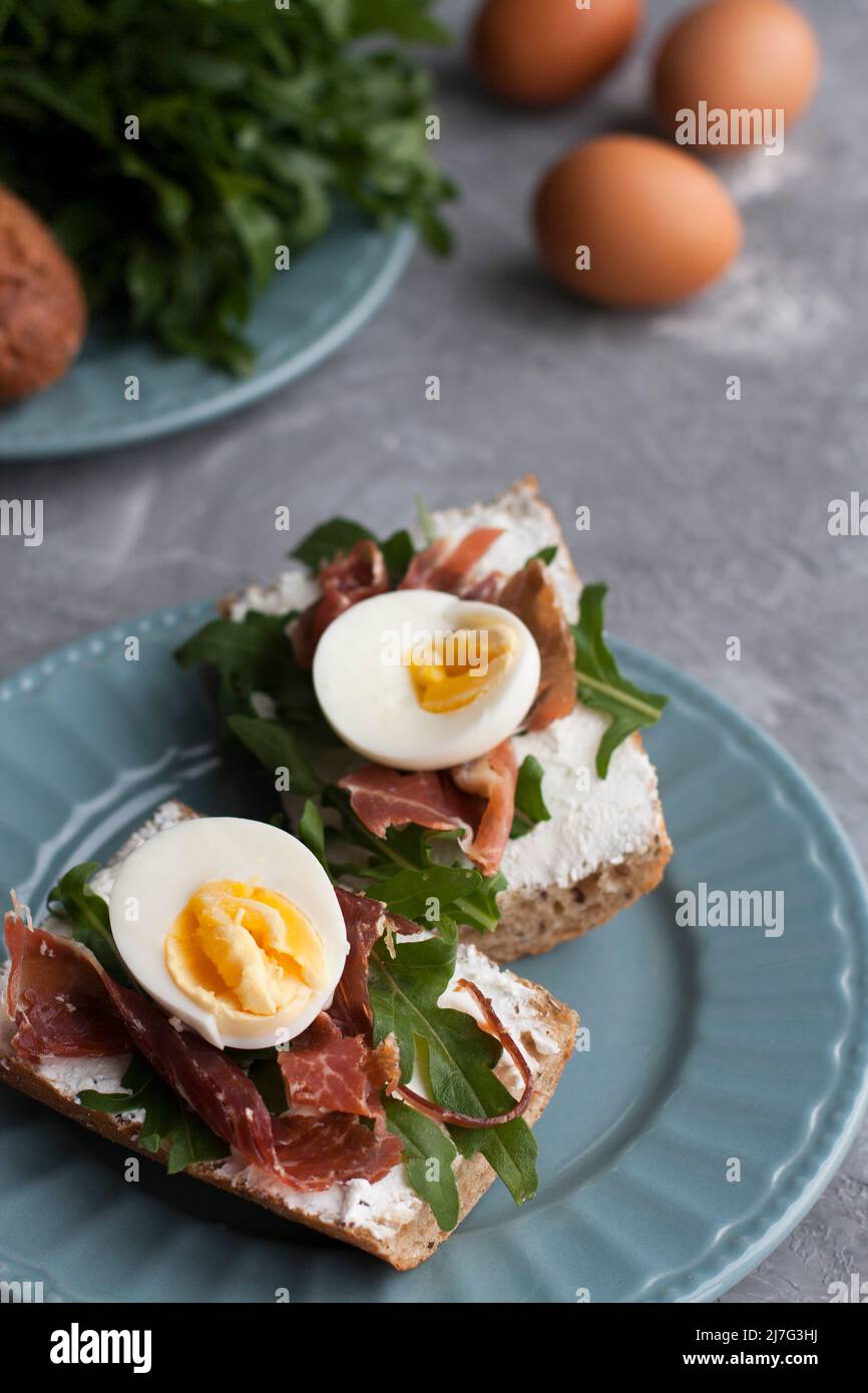 Sandwiches mit Vollkornbrot, hausgemachtem Käse, Rucola, Schinken und Ei. Gesunder Snack. Stockfoto