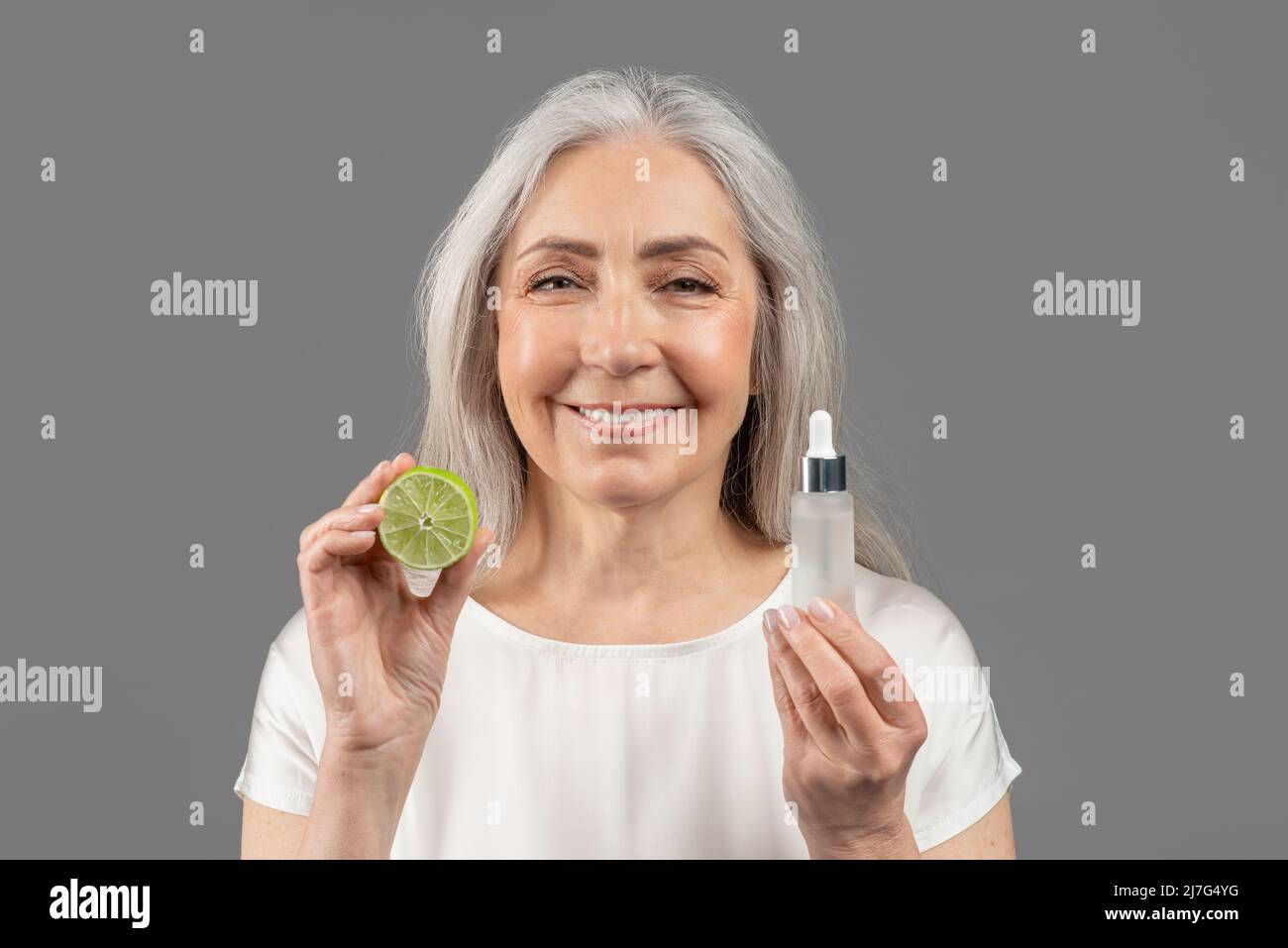 Tägliche Hautpflege. Feminine reife Frau, die für Bio-Kosmetik wirbt und Gesichtsserum mit Fruchtsäuren und Kalk zeigt Stockfoto