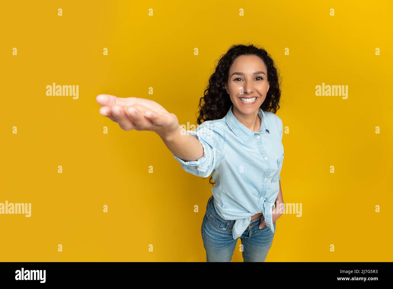 Lächelnde junge Frau, die die Hand ausstreckt und versucht, etwas zu halten Stockfoto