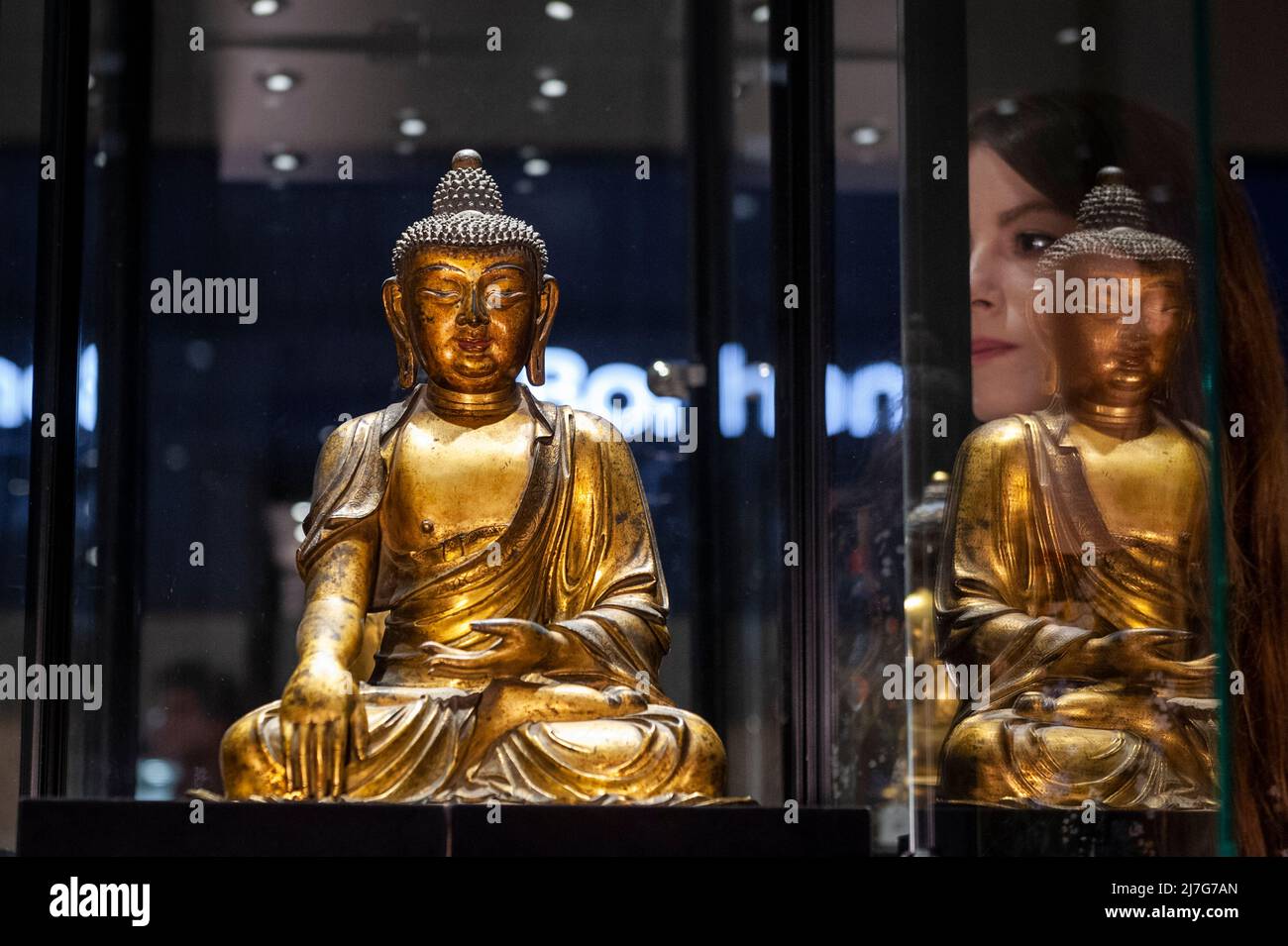 London, Großbritannien. 9 Mai 2022. Ein Mitarbeiter sieht „Eine sehr seltene große vergoldung Bronze-Figur von Buddha Shakyamuni“, Ming-Dynastie, (Est. £50.000 - £80.000) bei einer Vorschau auf Bonhams Verkauf von Fine Chinese Art in ihrer New Bond Street Galerie. Chinesische jades, Keramik, Lackwaren, Imperial- und Hoftextilien sowie Kunstwerke werden am 12. Mai zum Verkauf angeboten. Kredit: Stephen Chung / Alamy Live Nachrichten Stockfoto