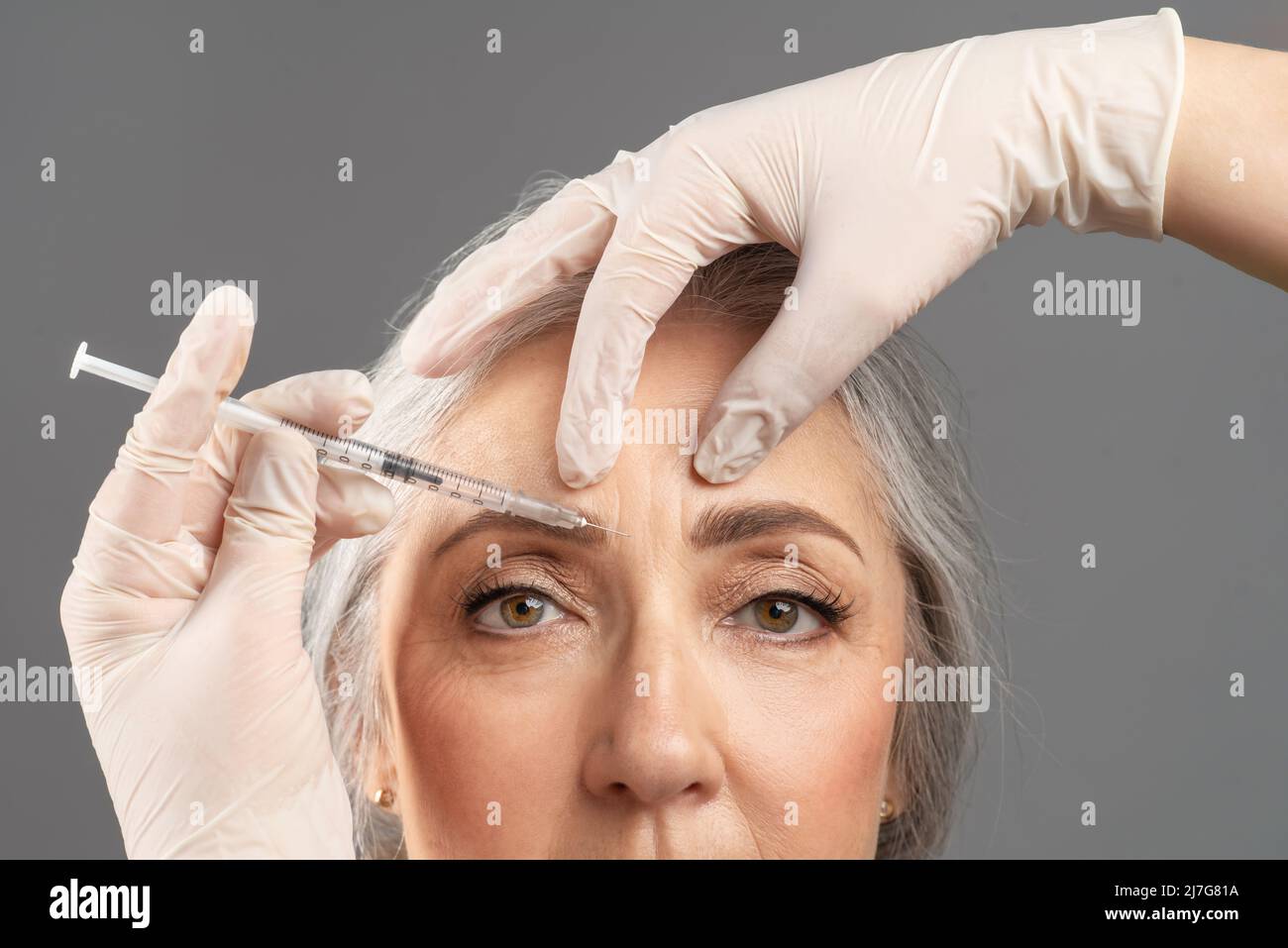 Reife Hautverjüngung. Nahaufnahme Porträt einer älteren Frau, die kosmetische Behandlung mit Schönheitsspritze erhält Stockfoto