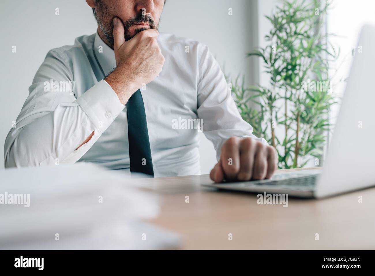 Geschäftsmann während eines Videoanrufs, Blick auf den Laptop-Bildschirm und Hören eines Sprechers, selektiver Fokus Stockfoto