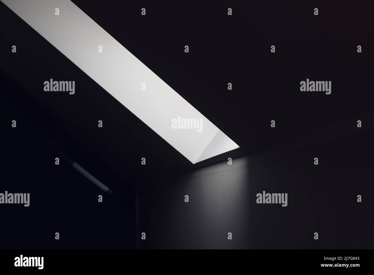 Dunkler Raum mit Lichtstreifen aus dem Dachfenster als abstrakter Hintergrund, monochromatisches Bild Stockfoto