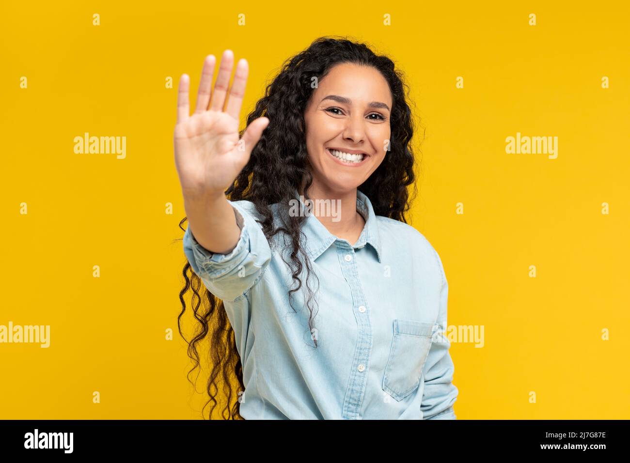 Porträt einer glücklichen jungen Frau mit Palmen im gelben Studio Stockfoto