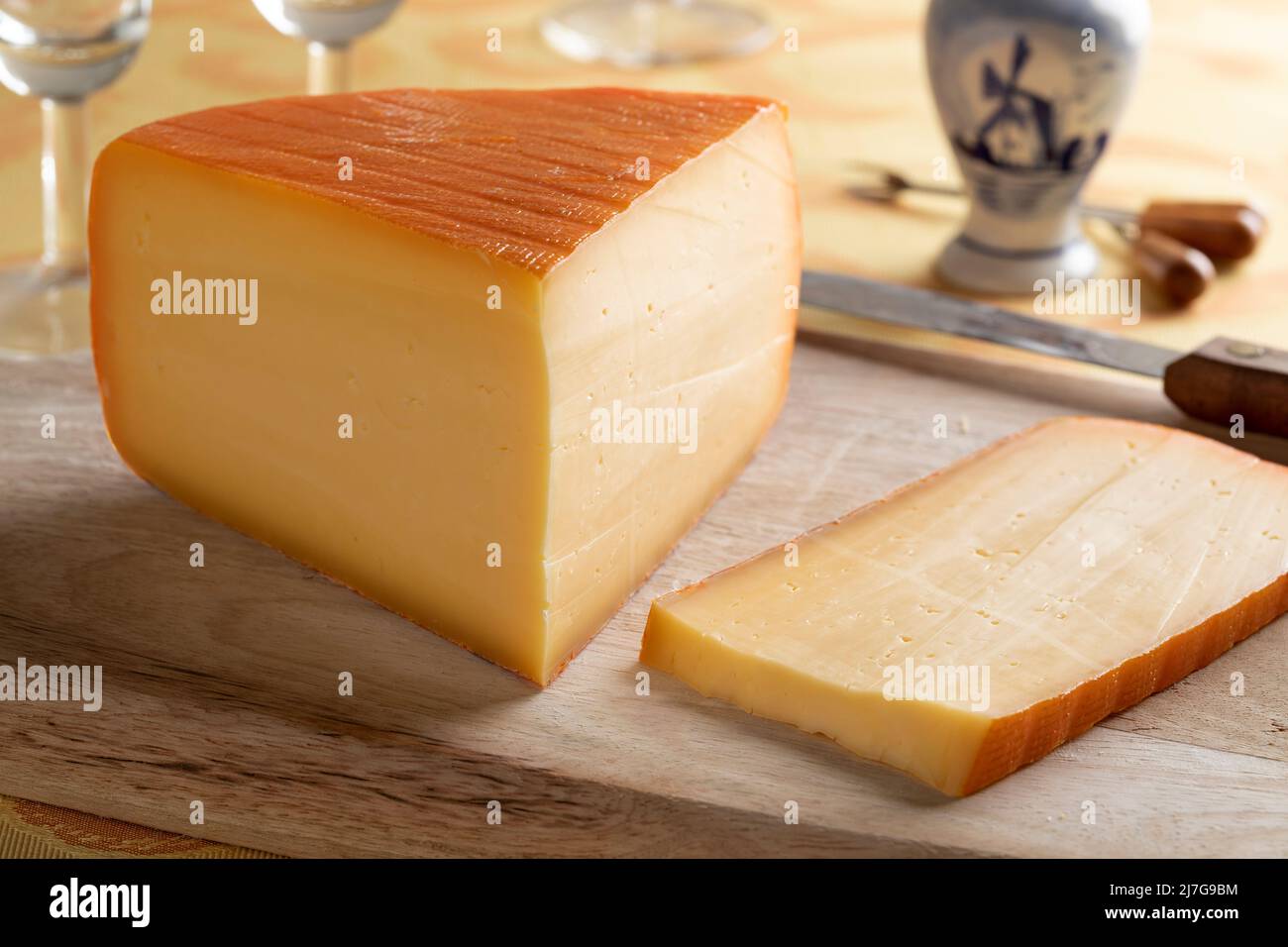 Ein Stück holländischer Kernhem-Käse und eine Scheibe auf einem Schneidebrett aus nächster Nähe Stockfoto