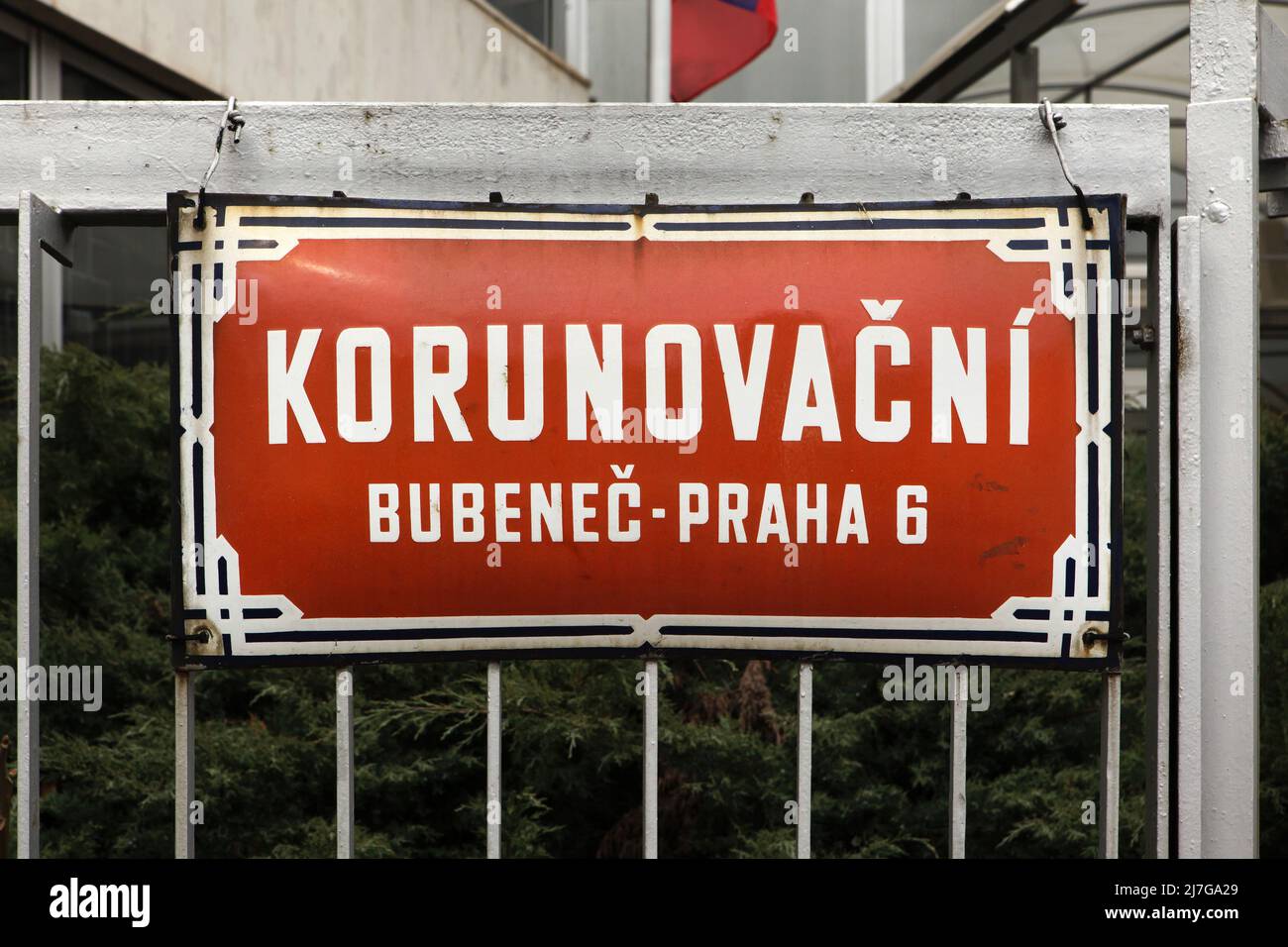 Straße Korunovační. Traditionelles rotes Straßenschild auf dem Gebäude der konsularischen Abteilung der russischen Botschaft im Stadtteil Bubeneč in Prag, Tschechische Republik. Im April 2022 wurde der Teil der Korunovační Straße, auf dem sich die Gebäude der russischen Botschaft befinden, in Ukrainische Heldenstraße (Ukrajinských hrdinů) umbenannt, um gegen die russische Invasion in der Ukraine im Jahr 2022 zu protestieren. Stockfoto