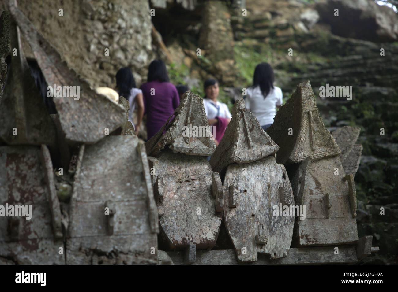 Hölzerner Sarkophag vor dem Hintergrund einheimischer Touristen an der traditionellen Grabstätte im Dorf Kete Kesu, Nord-Toraja, Süd-Sulawesi, Indonesien. Stockfoto