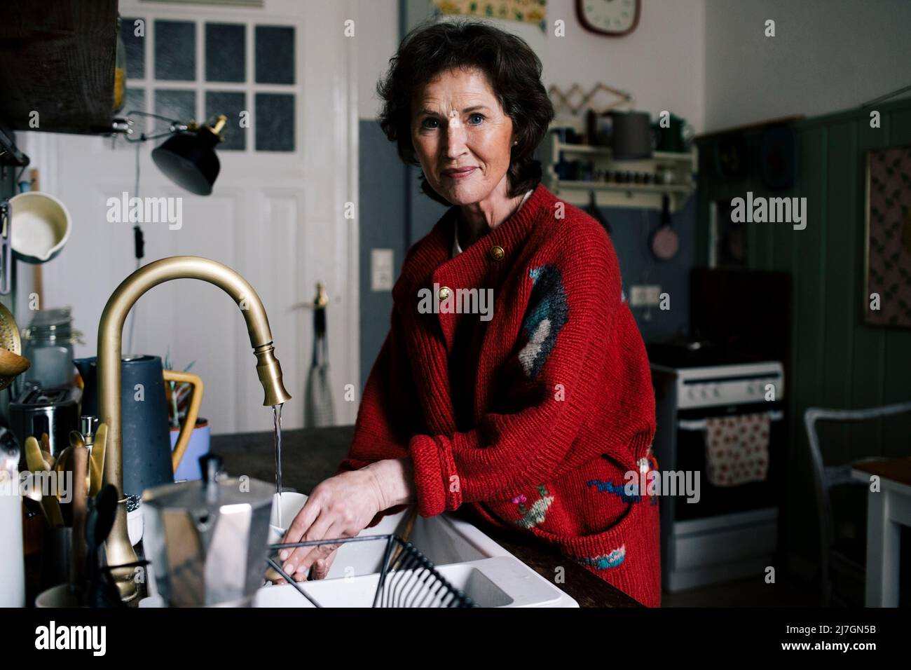 Ältere Frau, die zu Hause in der Küche Aufgaben erledigt Stockfoto