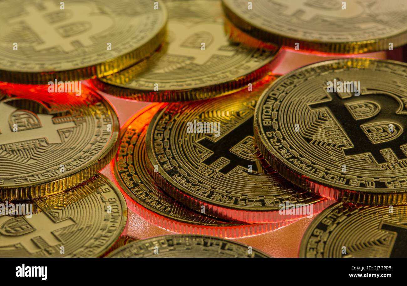 Bitcoin-Kryptowährung Nahaufnahme mit rot leuchtendem Hintergrund, was einen Rückgang des Handelspreises am Bärenmarkt anzeigt Stockfoto