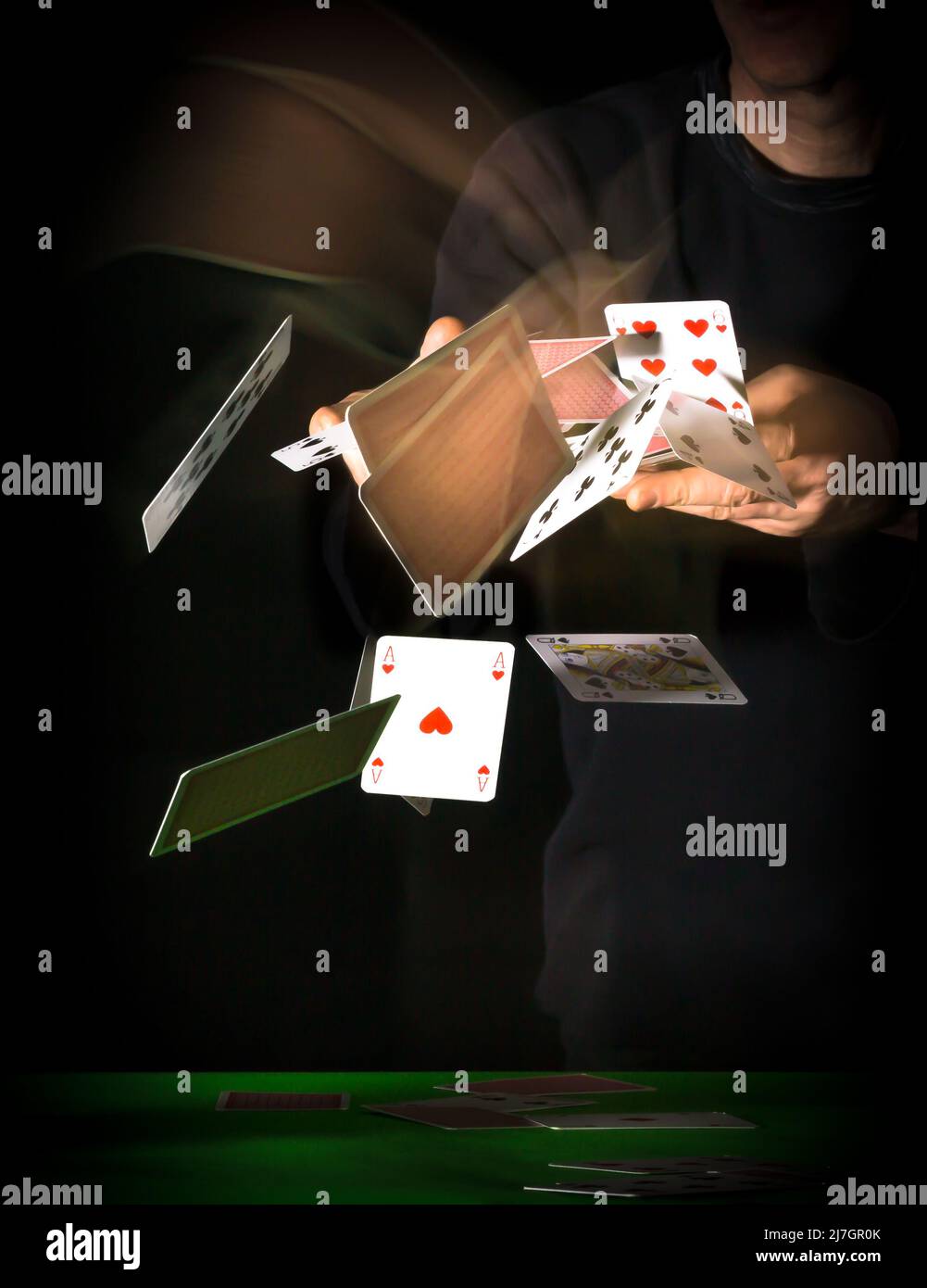 Spielkarten werden ausgeteilt oder geworfen und fliegen mit Bewegungsspuren auf schwarzem Hintergrund durch die Luft Stockfoto