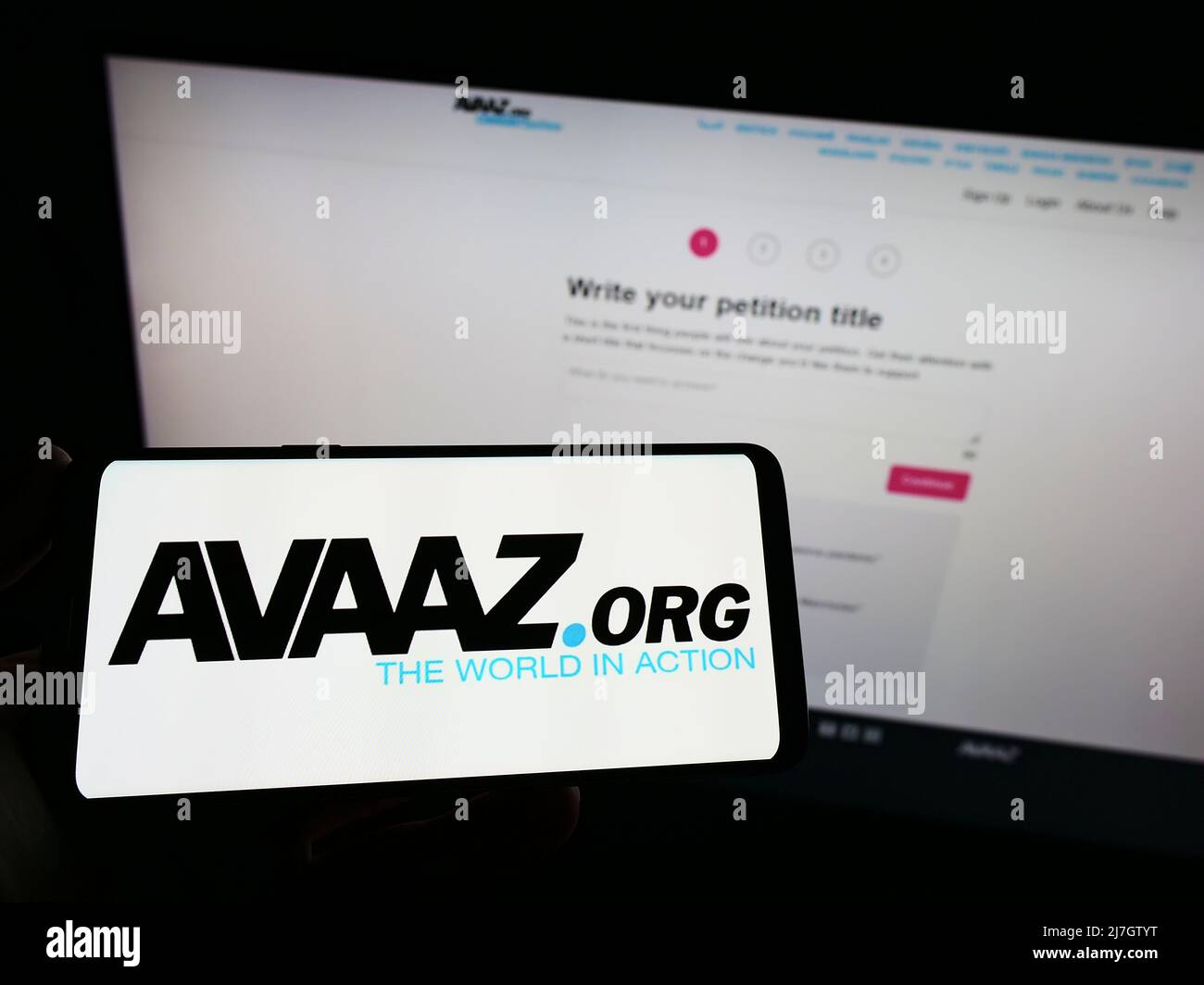 Person, die das Smartphone mit dem Logo der US-amerikanischen gemeinnützigen Organisation Avaaz auf dem Bildschirm vor der Website hält. Konzentrieren Sie sich auf die Telefonanzeige. Stockfoto