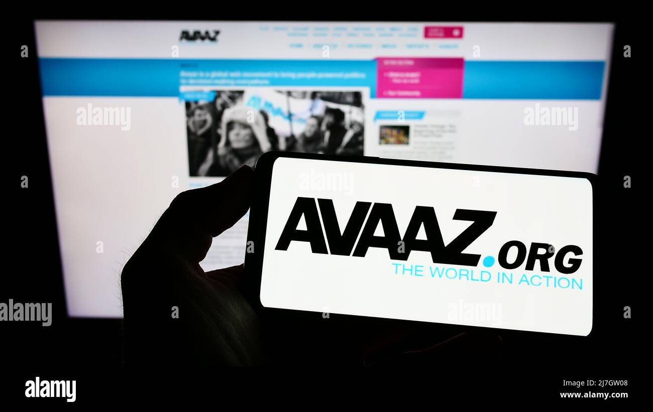 Person mit Mobiltelefon und Logo der amerikanischen gemeinnützigen Organisation Avaaz auf dem Bildschirm vor der Webseite. Konzentrieren Sie sich auf die Telefonanzeige. Stockfoto
