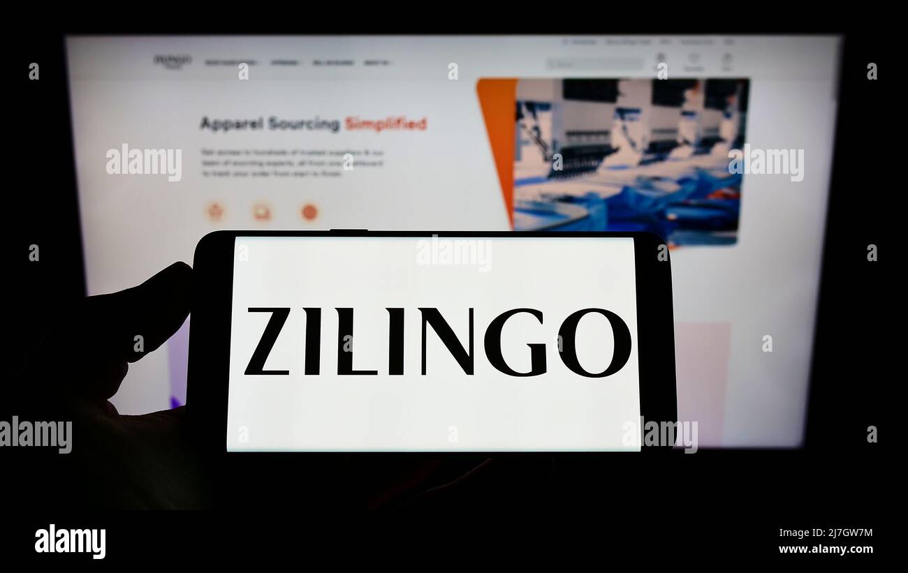 Person, die Mobiltelefon mit dem Logo des singapurischen E-Commerce-Unternehmens Zilingo Pte. Ltd. Auf dem Bildschirm vor der Webseite hält. Konzentrieren Sie sich auf die Telefonanzeige. Stockfoto