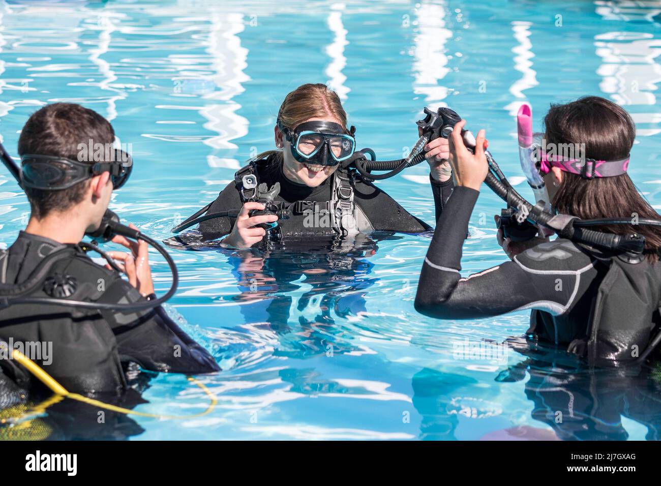 Scuba-Dive-Training im Pool mit einem lächelnden Instruktor, der zwei Studenten beibringt Stockfoto
