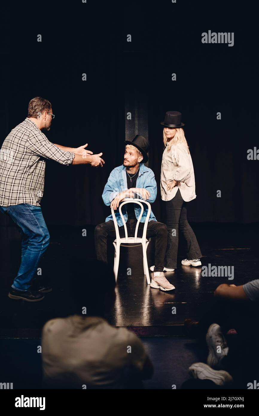 Die ganze Länge des Mannes führt Künstler sitzen auf einem Stuhl, während Proben mit Frau auf der Bühne Stockfoto