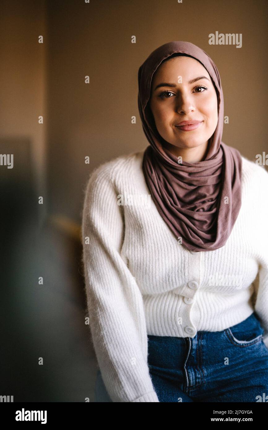 Porträt einer lächelnden jungen Frau, die zu Hause einen Hijab trägt Stockfoto