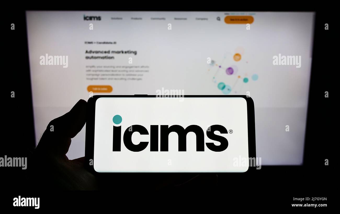 Person, die Mobiltelefon mit dem Logo des US-amerikanischen Human Resources Software-Unternehmens iCIMS Inc. Auf dem Bildschirm vor der Webseite hält. Konzentrieren Sie sich auf die Telefonanzeige. Stockfoto