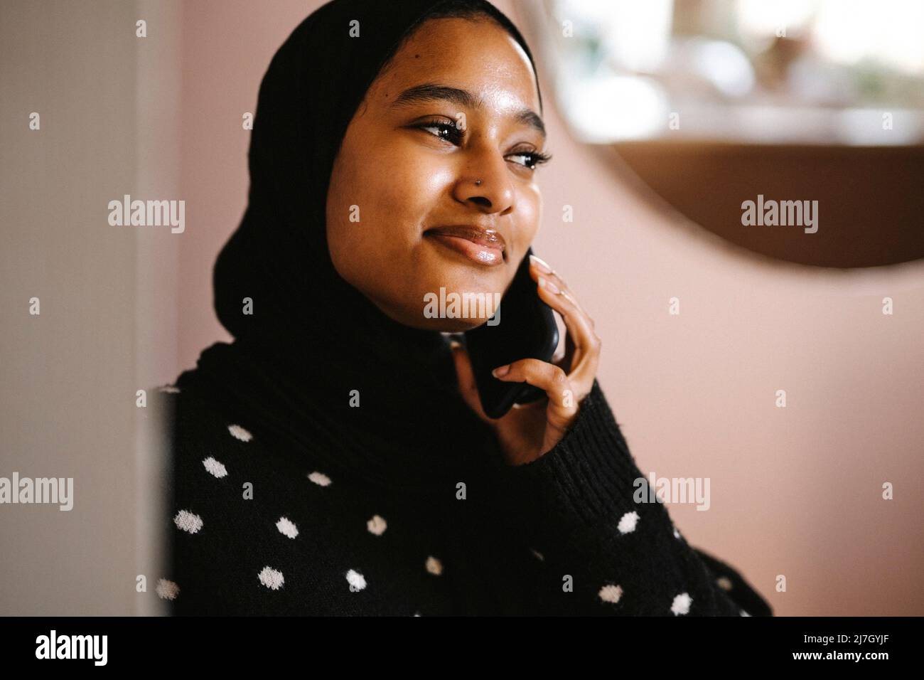 Lächelnde Frau, die zu Hause auf dem Smartphone spricht Stockfoto
