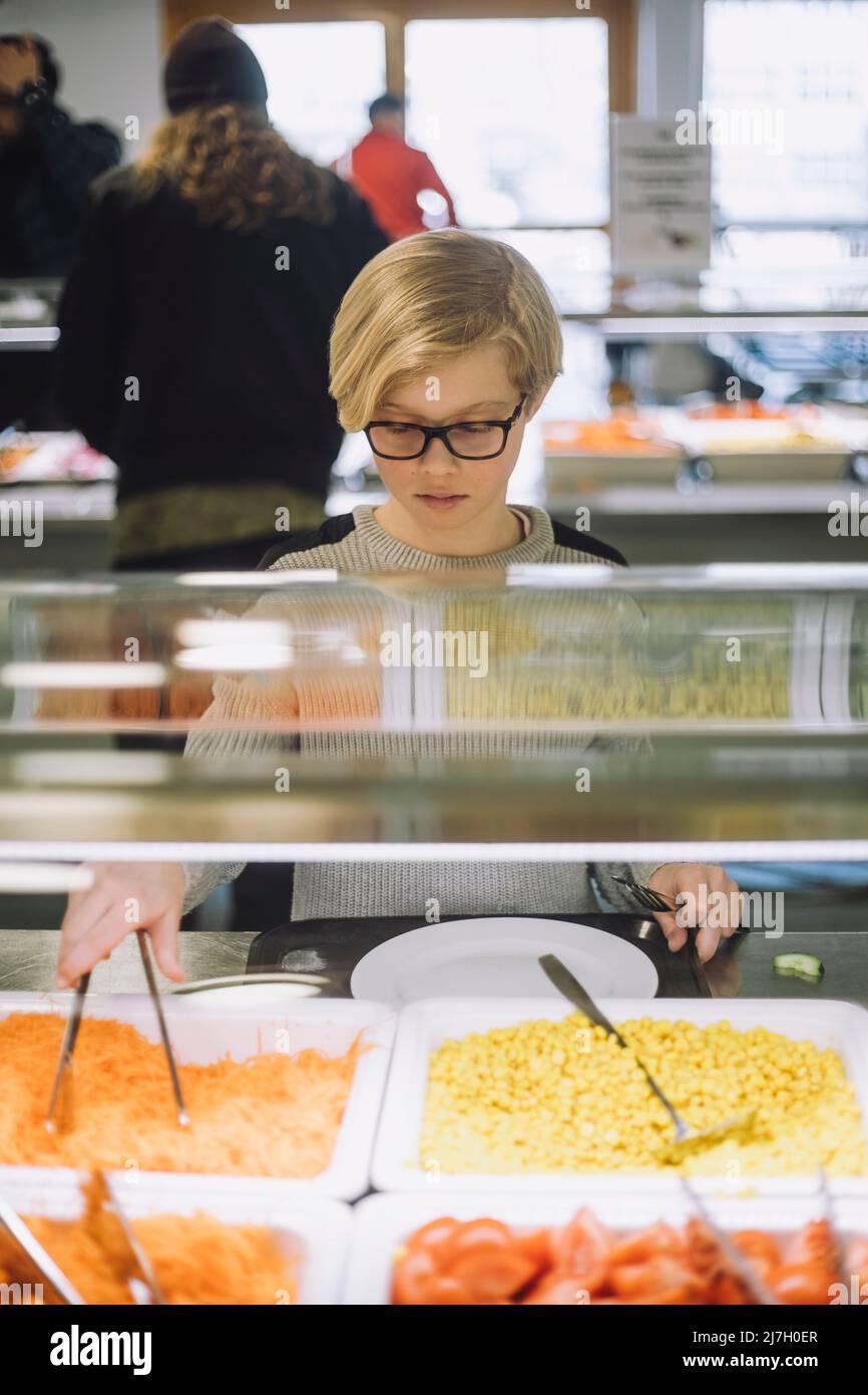 Junge, der während der Mittagspause in der Cafeteria Essen nimmt Stockfoto