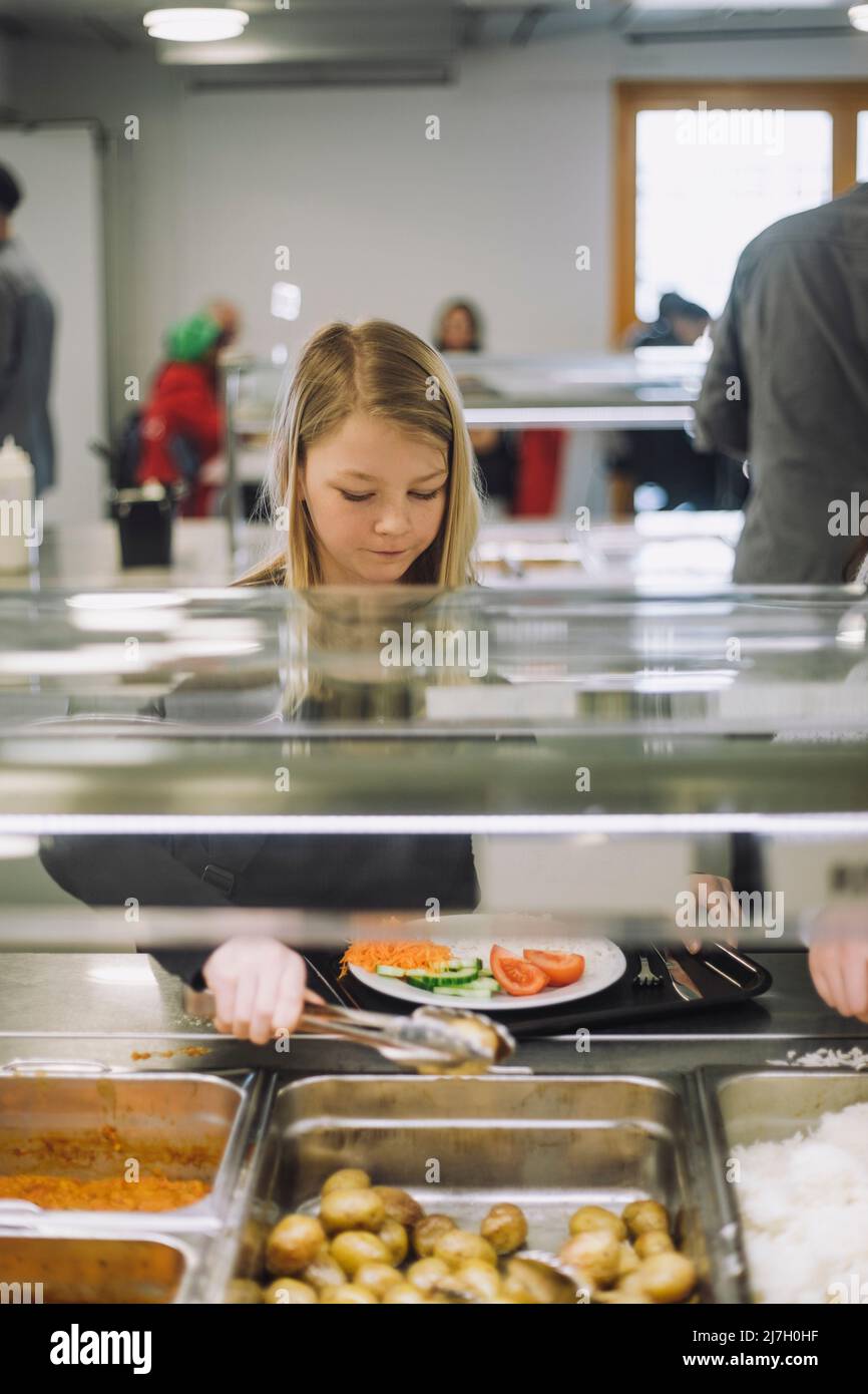 Mädchen nimmt während der Mittagspause in der Cafeteria Essen aus der Food Bar Stockfoto