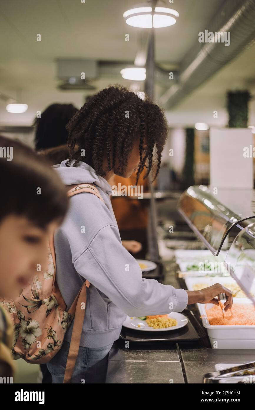 Seitenansicht des Schulmädchen während der Mittagspause in der Cafeteria Stockfoto