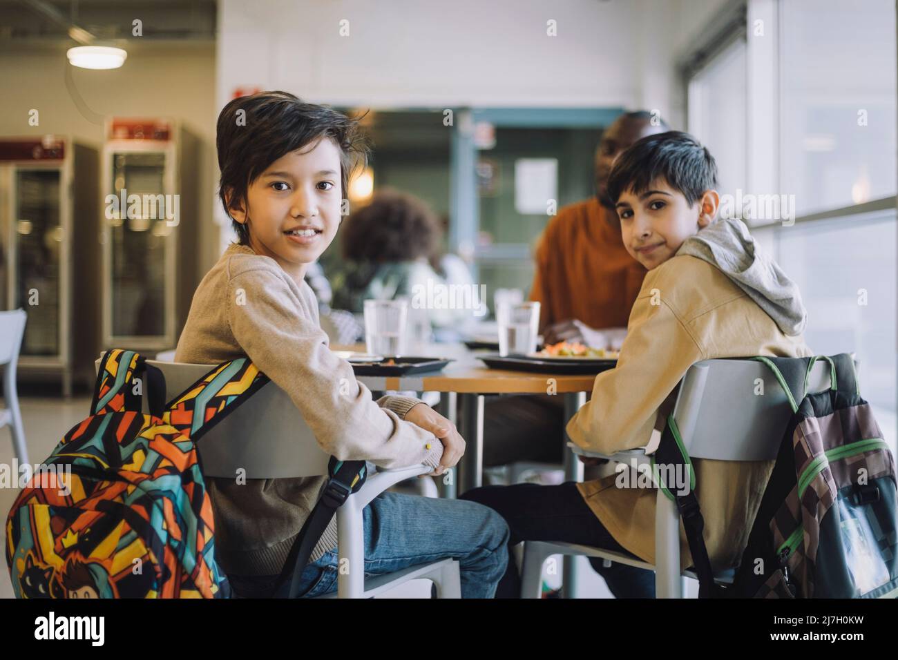 Porträt von Schülern, die während der Mittagspause auf dem Stuhl sitzen und über die Schulter schauen Stockfoto