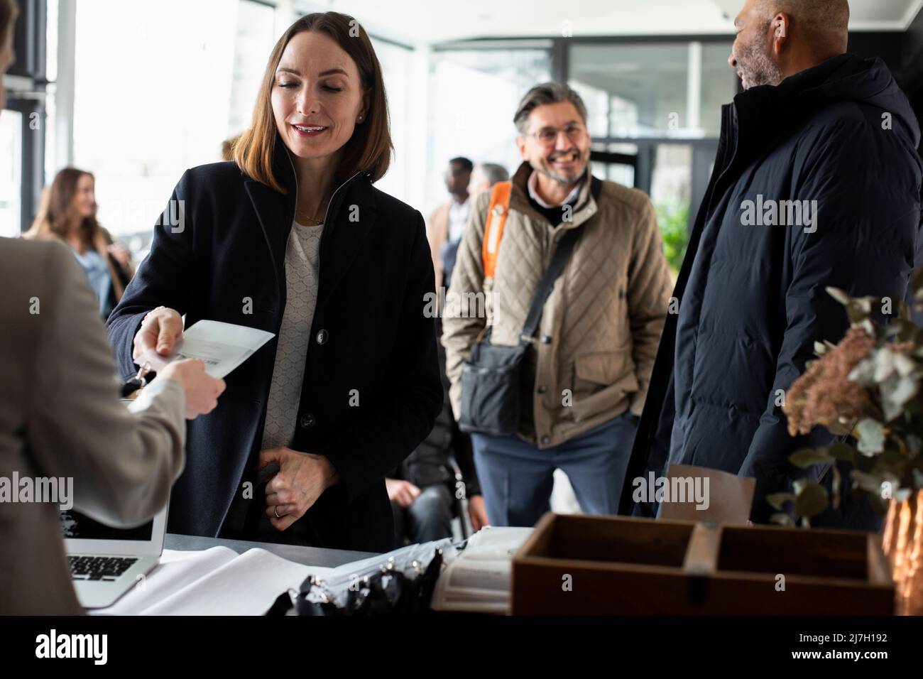 Geschäftsfrau, die am Schalter der Rezeption einen Personalausweis entgegennimmt Stockfoto