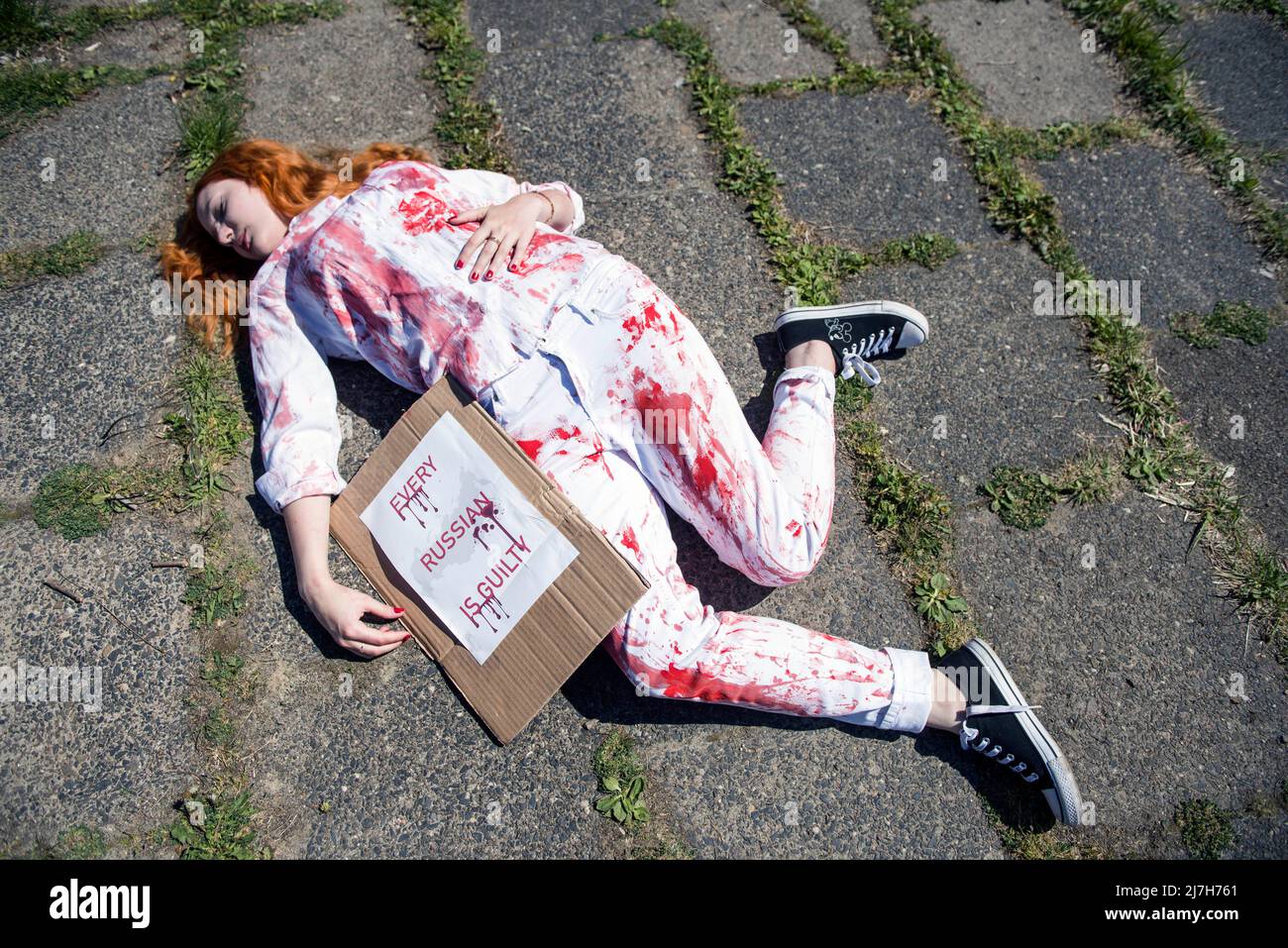 Warschau, Polen. 09.. Mai 2022. Ein Aktivist liegt auf dem Boden, als er die zivilen Opfer des Krieges in der Ukraine symbolisiert. Hunderte von Ukrainern und polnischen Aktivisten protestierten auf einem Warschauer Friedhof vor Soldaten der Roten Armee, die während des Zweiten Weltkriegs starben Der russische Botschafter in Polen, Sergej Andreev, wurde von Demonstranten, die gegen den Krieg in der Ukraine waren, bei einer jährlichen Veranstaltung zum Tag des Sieges zum Gedenken an das Ende des Zweiten Weltkriegs mit roter Farbe angestrichen Botschafter Sergey Andreev kam am Tag des Sieges auf dem sowjetischen Soldatenfriedhof an, um Blumen zu legen, aber der Diplomat und seine Delegation waren gezwungen, das Gebiet zu verlassen, ein Stockfoto