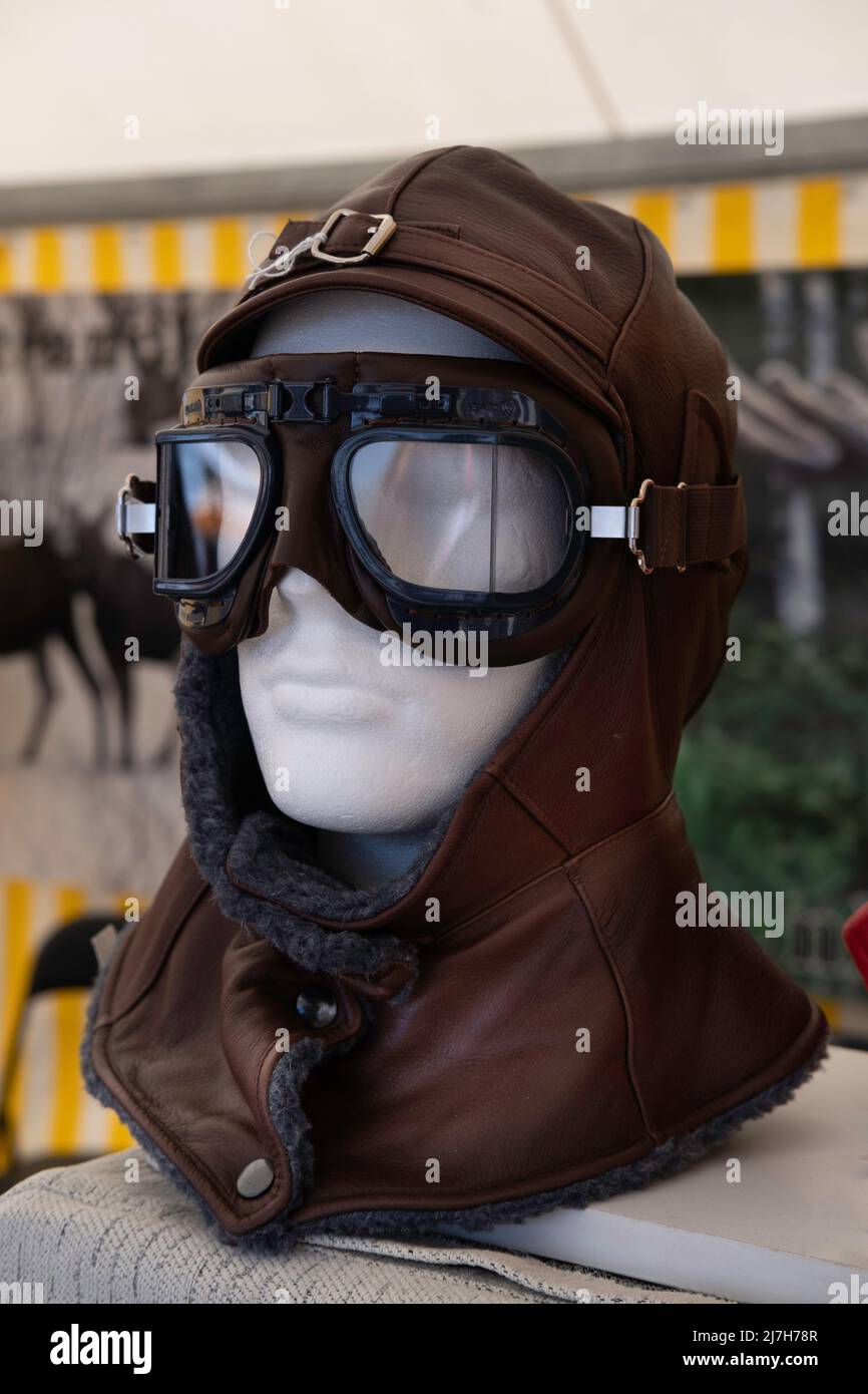 Winddichter, mit Fell gefütterter Lederhut mit passender Sonnenbrille auf einem Styropor-Kopf in einem Marktstand. Gesichtsschutz im Schnee oder auf dem Motorrad Stockfoto