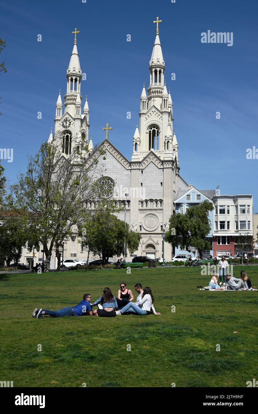 Der Mann mit einer Motorrad-Clubjacke von Hell's Angels geht mit seinem Hund vor die katholische Kirche der Heiligen Peter und Paul in San Francisco, Kalifornien. Stockfoto