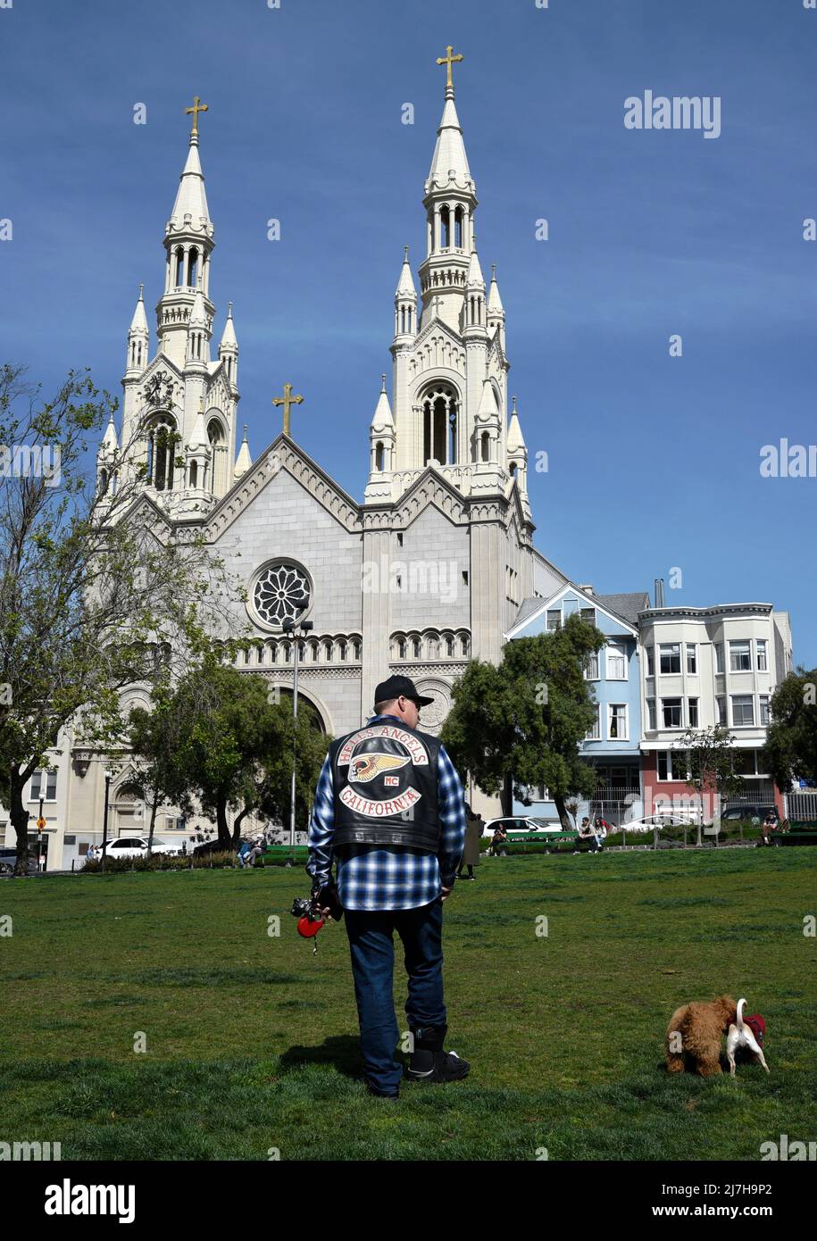 Der Mann mit einer Motorrad-Clubjacke von Hell's Angels geht mit seinem Hund vor die katholische Kirche der Heiligen Peter und Paul in San Francisco, Kalifornien. Stockfoto