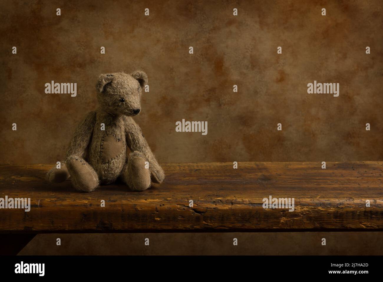 Graubrauner kleiner Teddybär auf einem rustikalen alten Holzregal. Dies ist für digitales Compositing geeignet. Stockfoto