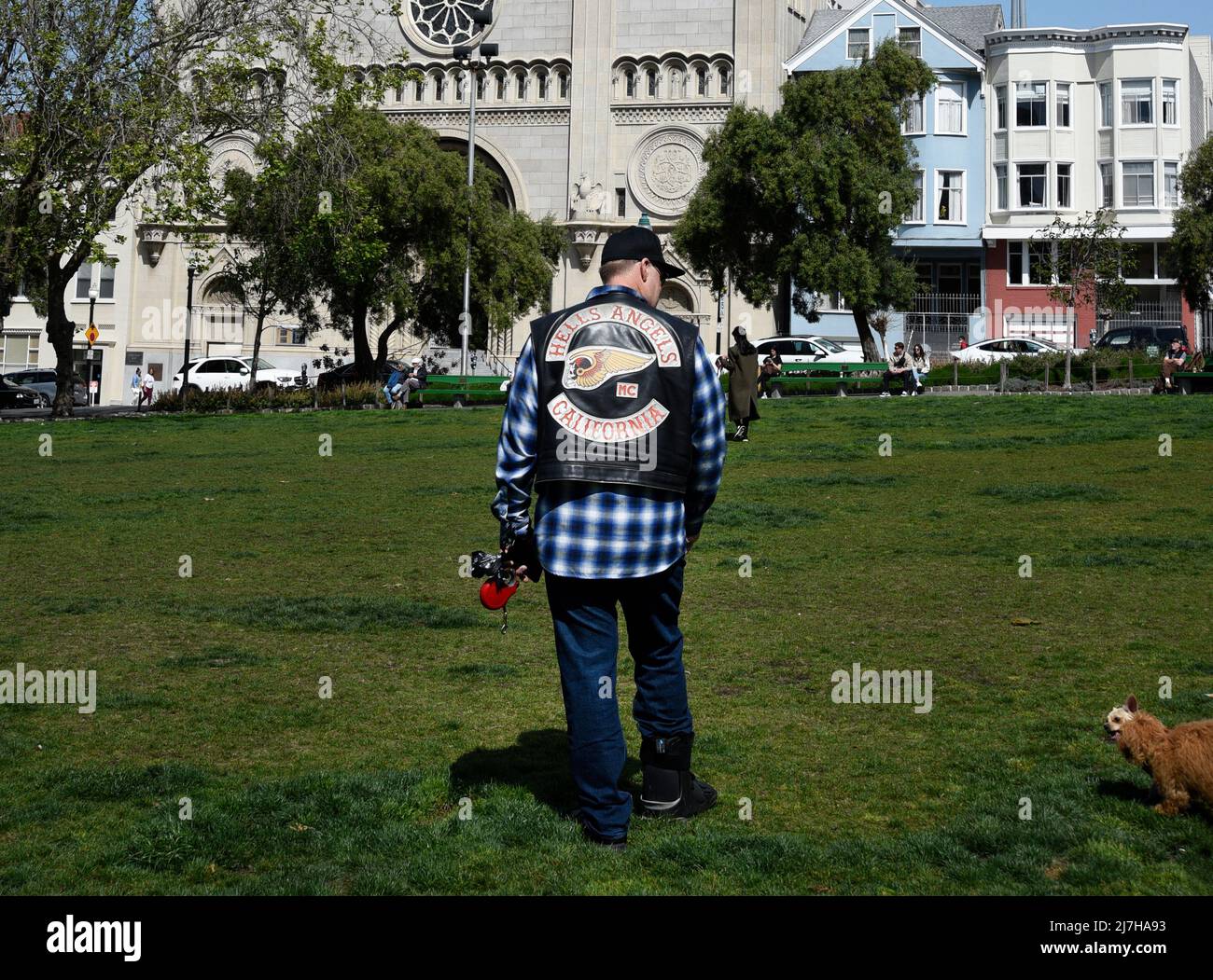 Ein Mann mit einer Motorrad-Clubjacke von Hell's Angels geht mit seinem Hund vor die katholische Kirche St. Peter und Paul in San Francisco, Kalifornien. Stockfoto
