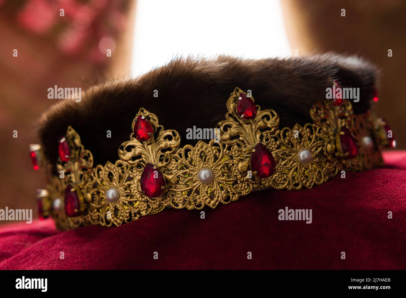 Goldene Krone mit Hintergrundbeleuchtung und roten Samtvorhängen fotografiert Stockfoto