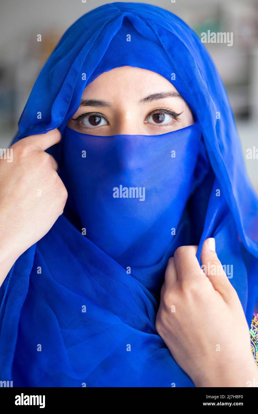 Porträt einer jungen muslimischen Frau, die einen Teil ihres Gesichts mit einem charakteristischen islamischen Schleier bedeckt. Nahaufnahme. Stockfoto