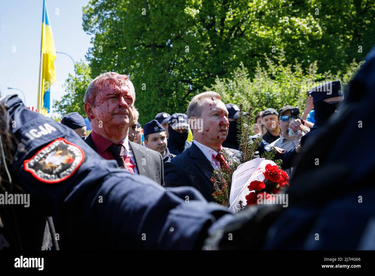 Warschau, Polen. 09.. Mai 2022. Der Botschafter der Russischen Föderation Sergej Andreew, umgeben von einem polnischen Polizeibeamten, bewegt sich in Richtung seines Autos, das mit gefälschtem Blut bedeckt ist. Am 77.. Jahrestag des Sieges der Roten Armee über Nazi-Deutschland traten ukrainische Aktivisten auf dem sowjetischen Soldatenfriedhof in Warschau auf, als sie gegen die russische Invasion in der Ukraine protestierten. Aktivisten verboten der russischen Delegation unter der Leitung von Sergej Andreev, dem Botschafter der Russischen Föderation in Polen, den Eintritt in den Friedhof. Während dieses Versuchs wurden Diplomaten von ukrainischen Aktivisten mit gefälschtem Blut übergossen. Stockfoto