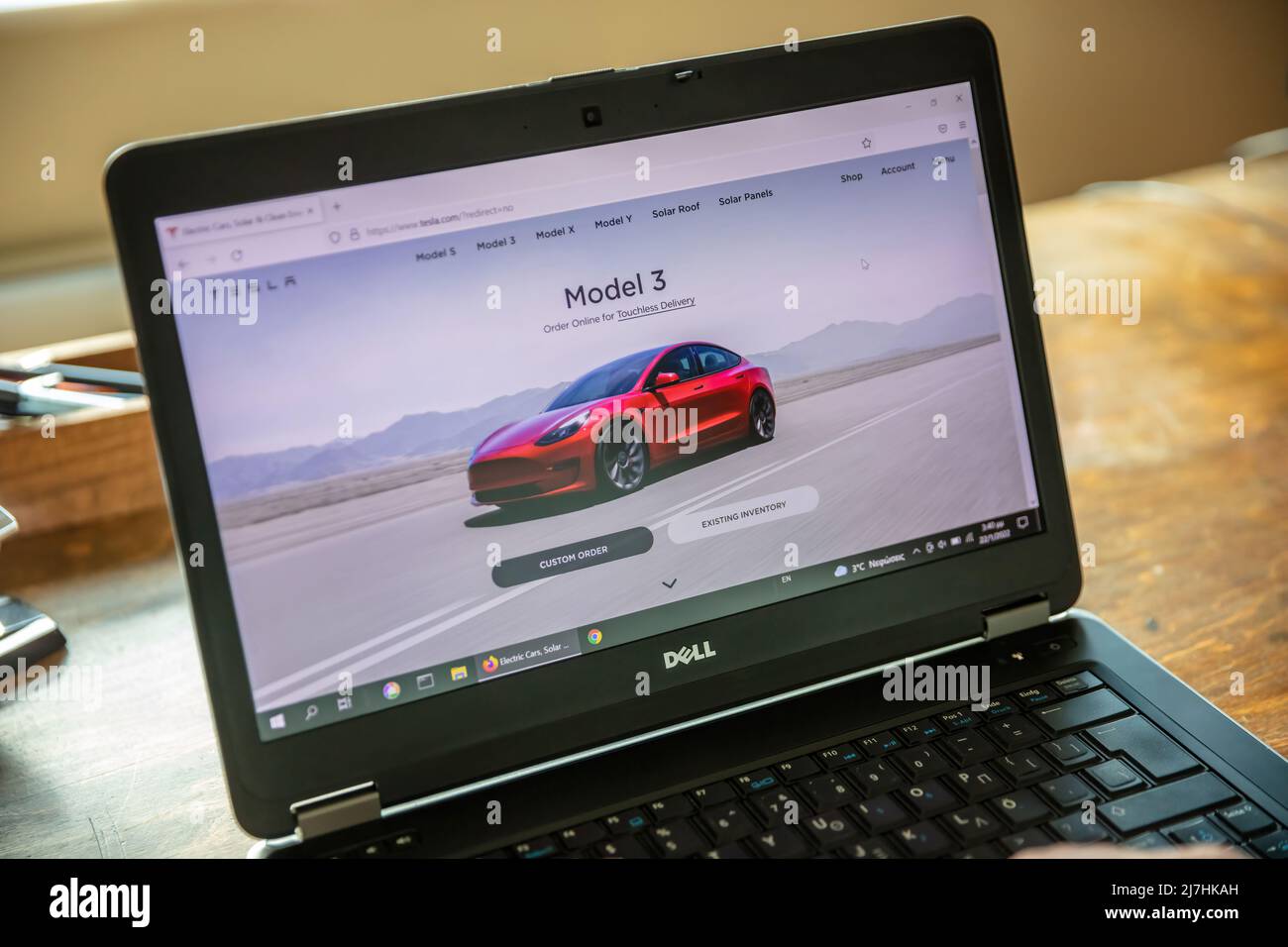 Griechenland, Athen, Januar 23 2022. TESLA FAHRZEUGAUSWAHL. Ad, online rot Tesla Modell 3 Elektro-Auto. Computer Laptop auf Holztisch, Nahaufnahme Stockfoto