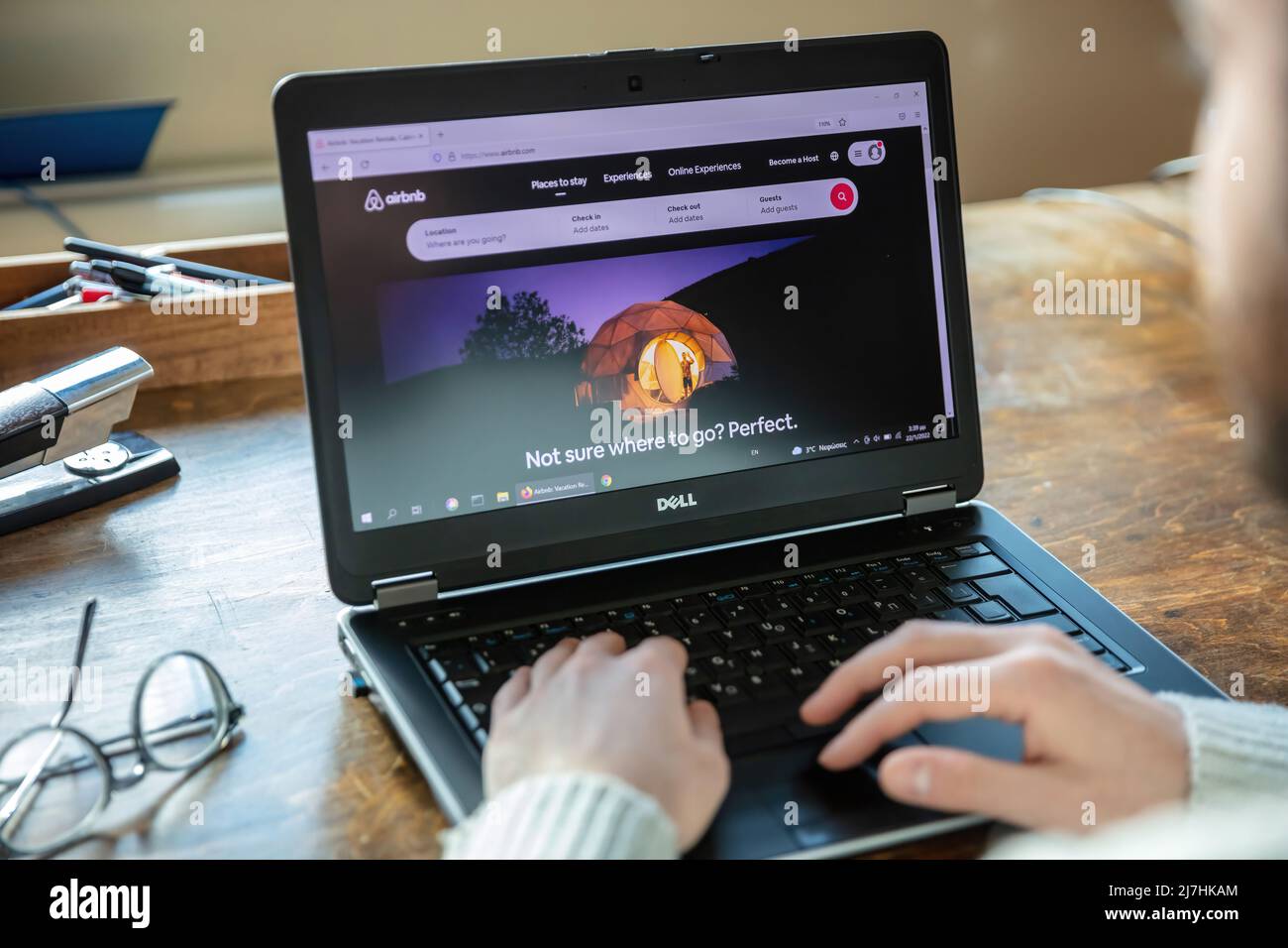 Griechenland, Athen, Januar 23 2022. AIRBNB Home Search, Online-Buchung von Unterkünften App. Kurzfristige Unterkunft mieten auf Computer-Bildschirm. Männliche Hand auf Laptop Stockfoto