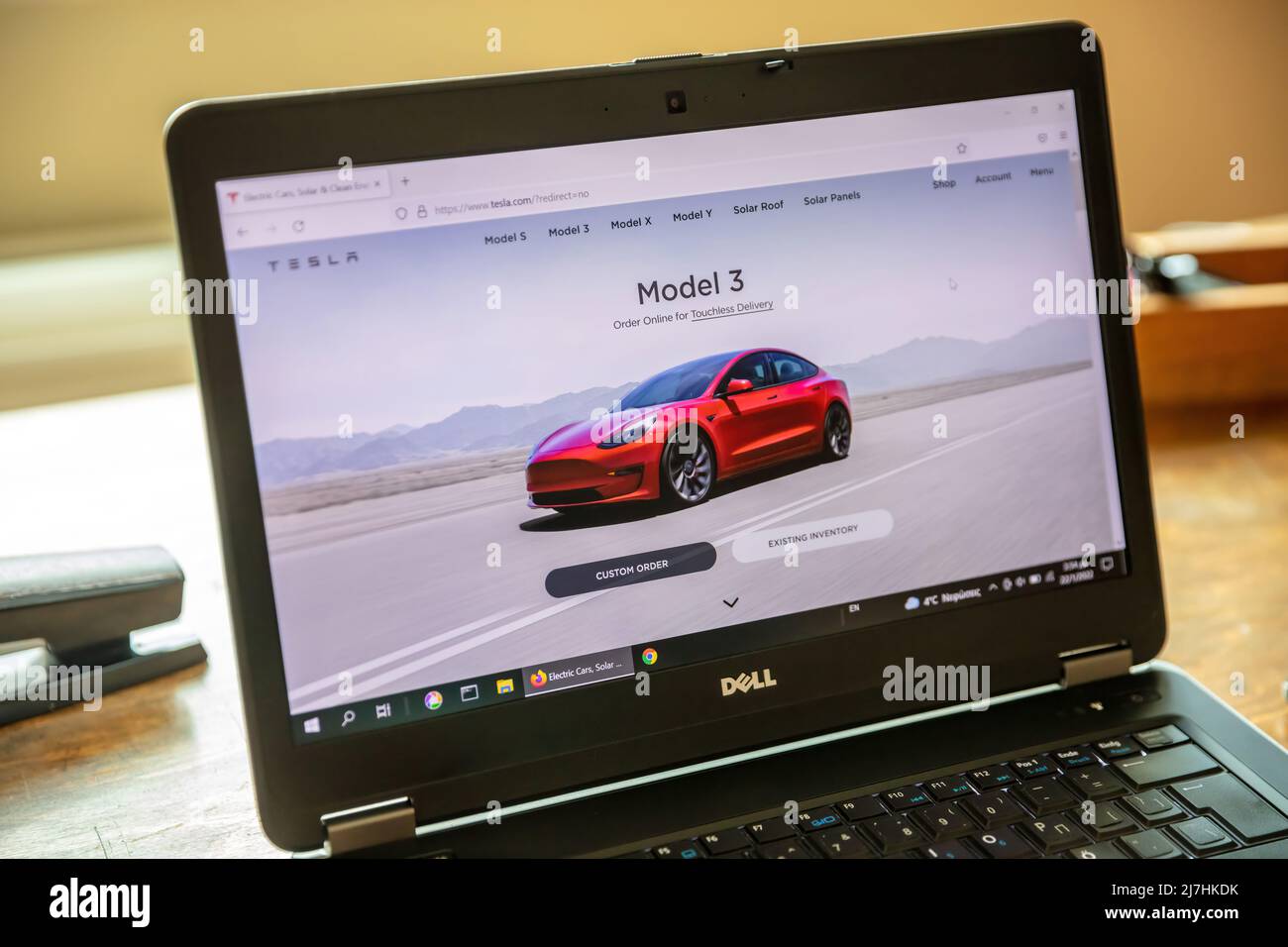 Griechenland, Athen, Januar 23 2022. TESLA FAHRZEUGAUSWAHL. Ad, online rot Tesla Modell 3 Elektro-Auto. Computer Laptop auf Holztisch, Nahaufnahme Stockfoto