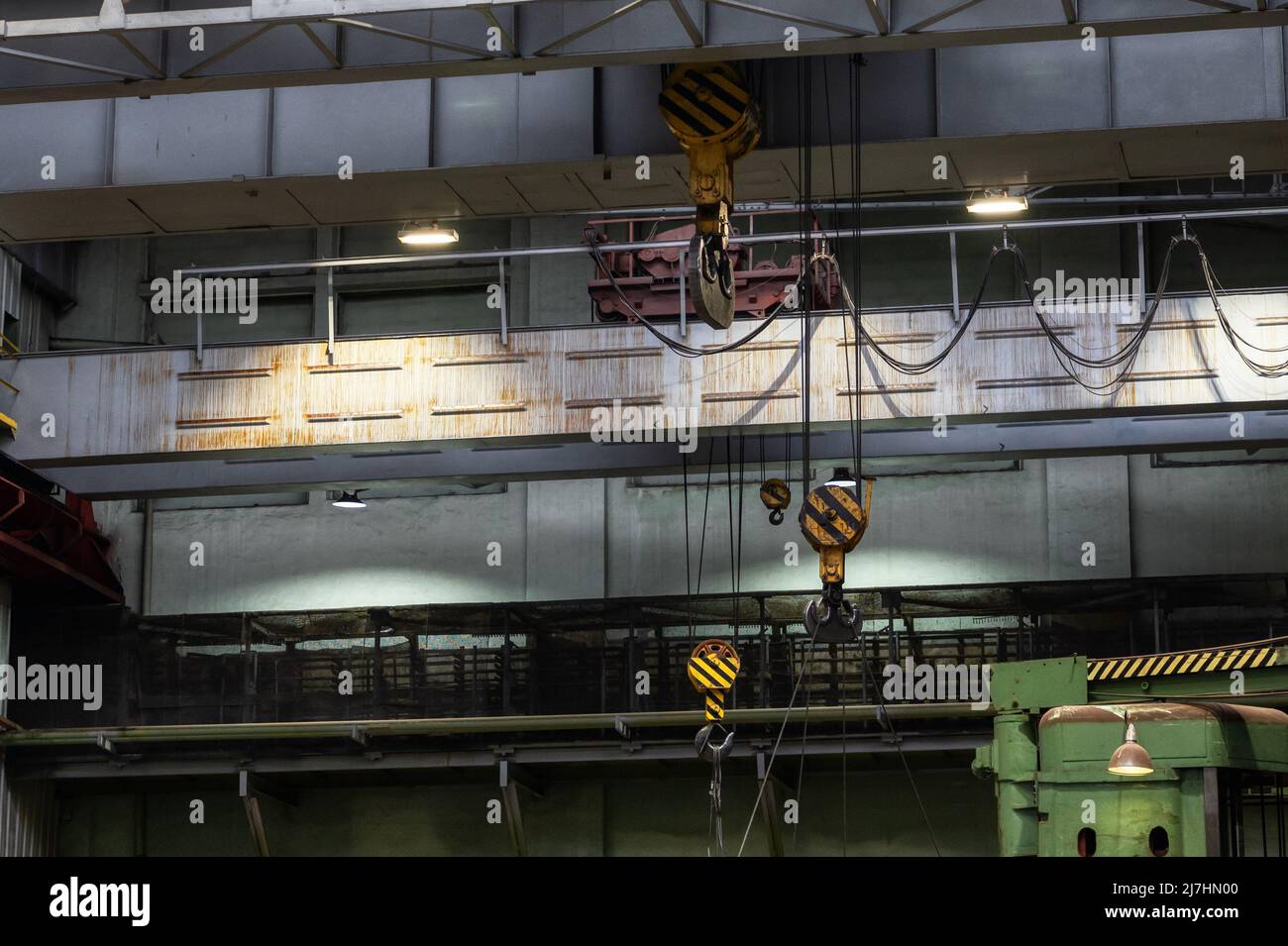 Krane mit starken Haken unter der Decke der Industriehalle Stockfoto