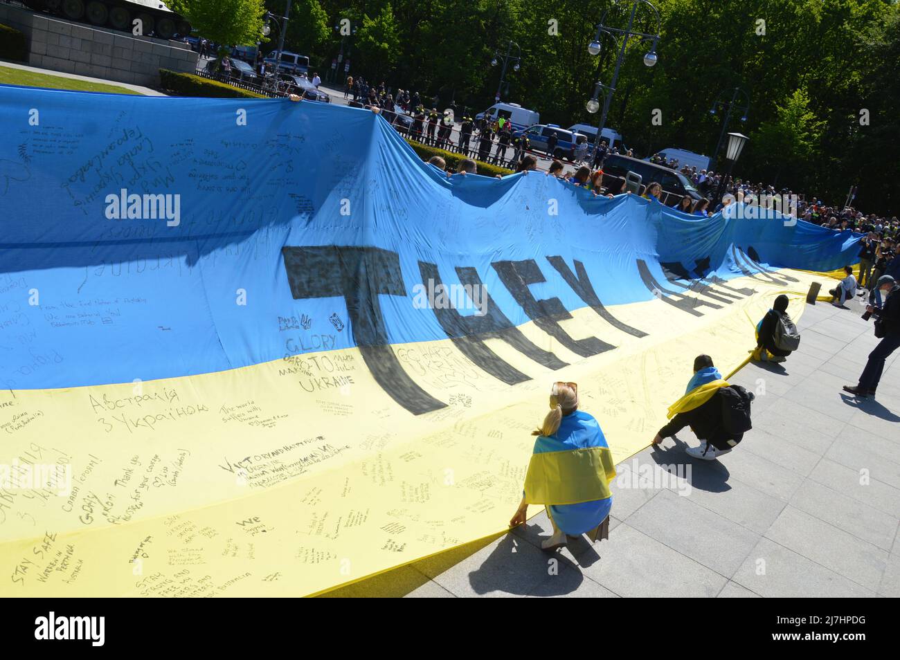 Am 8. Mai 2022 halten Menschen eine große ukrainische Flagge am sowjetischen Kriegsdenkmal im Tiergarten in Berlin. Stockfoto