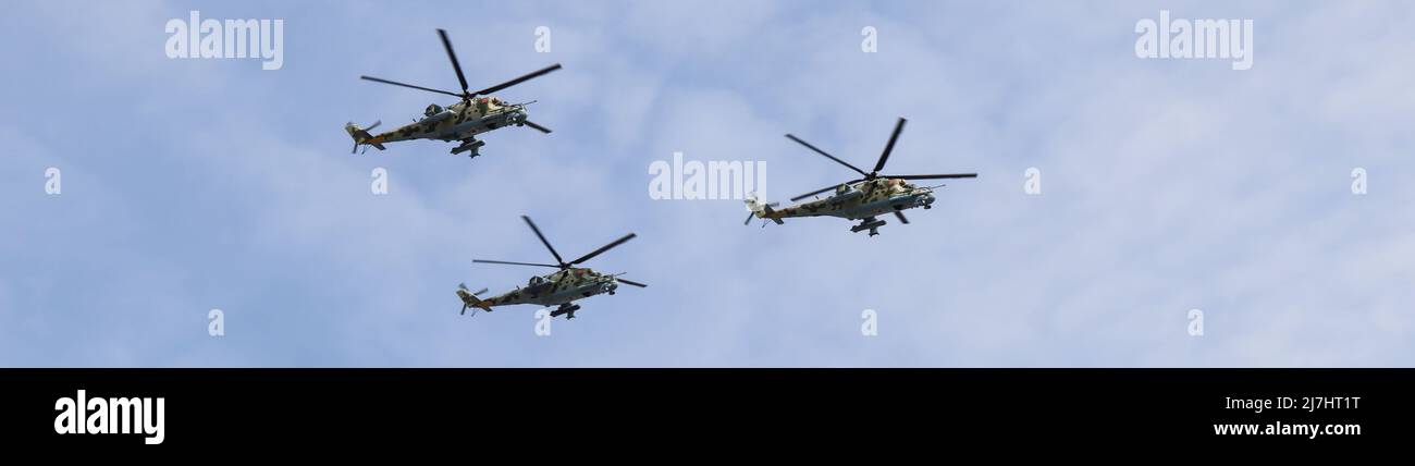 Moskau, Russland, 2022. Mai: Banner mit dem Flug von drei Mi-24-Militärhubschraubern am Himmel. Die Hauptprobe der Militärparade. Stockfoto