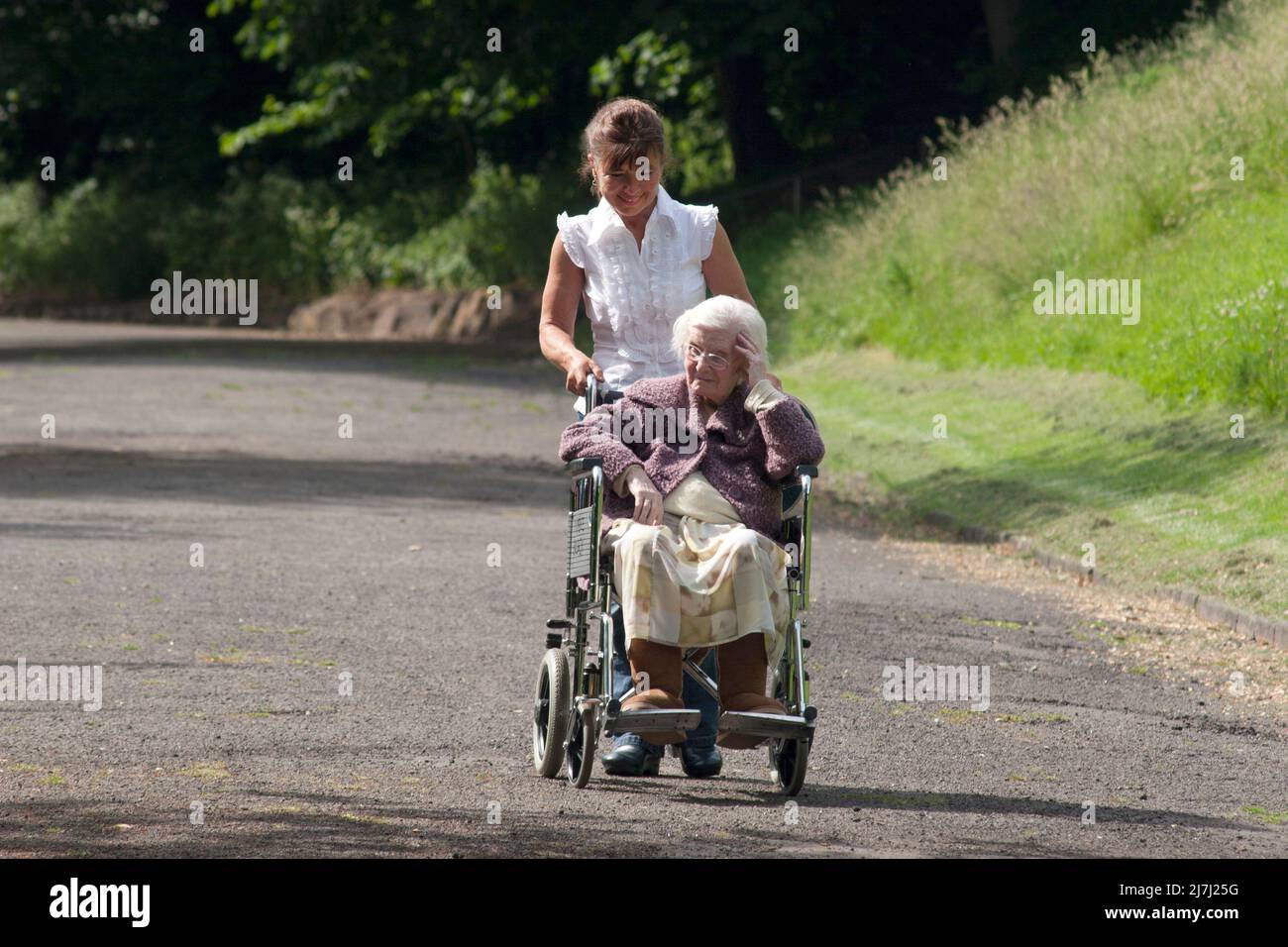 Eine Frau mit einer sehr alten Dame im Rollstuhl Stockfoto