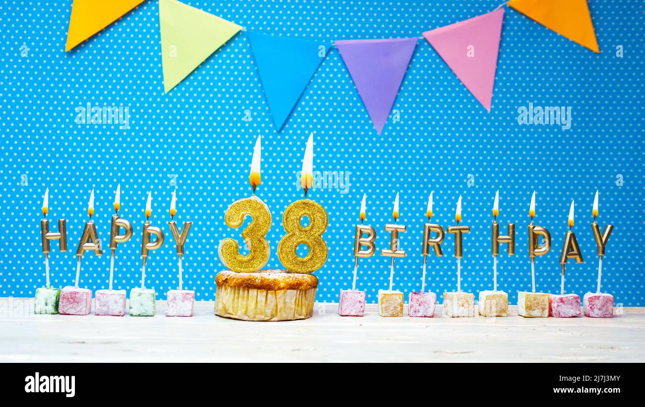 Alles gute zum Geburtstag aus Kerzenbuchstaben auf blauem Hintergrund mit weißem Tupfen-Kopierraum. Alles gute zum Geburtstag Cupcake mit brennender goldener Kerze Stockfoto