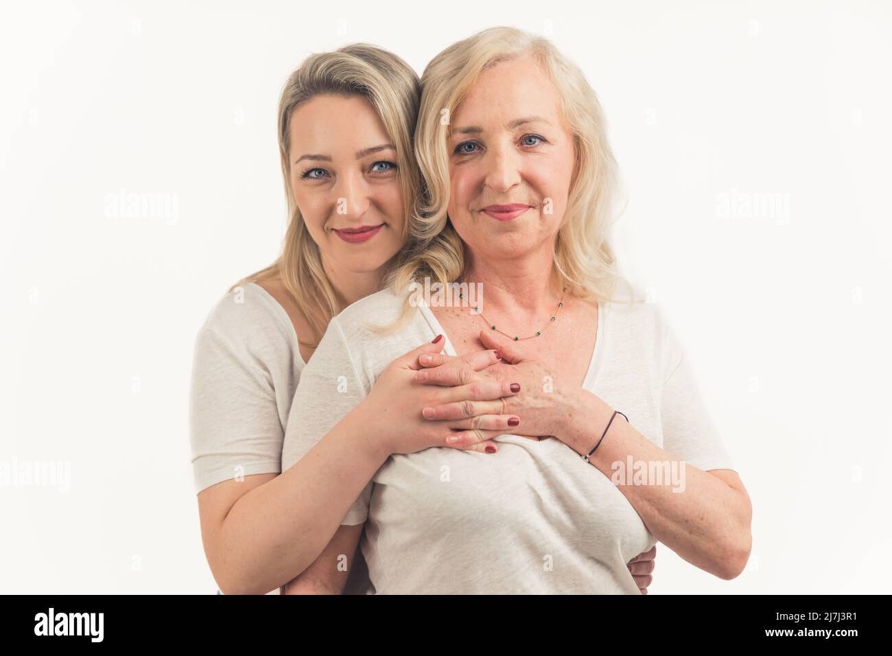 Erwachsene Tochter umarmt lächelnde blonde Mutter von hinten, Familiengeneration Konzept. Hochwertige Fotos Stockfoto