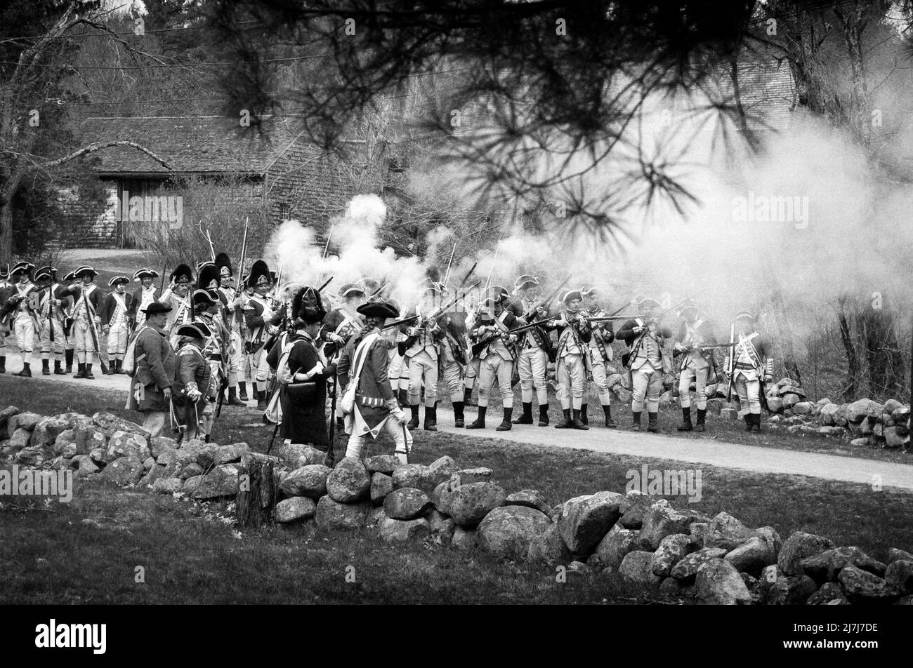 Reenactment Redcoats feuern ihre Musketen auf Minutemen während der Simulation eines Angriffs von den Redcoats auf der Battle Road in Lexington auf Patriots Weeken Stockfoto