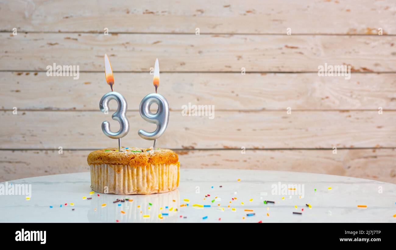 Alles gute zum Geburtstag silberne Ziffern auf weißen Brettern Hintergrund kopieren Raum. Schöne Geburtstagskarte mit einem Cupcake mit brennender Kerze Stockfoto