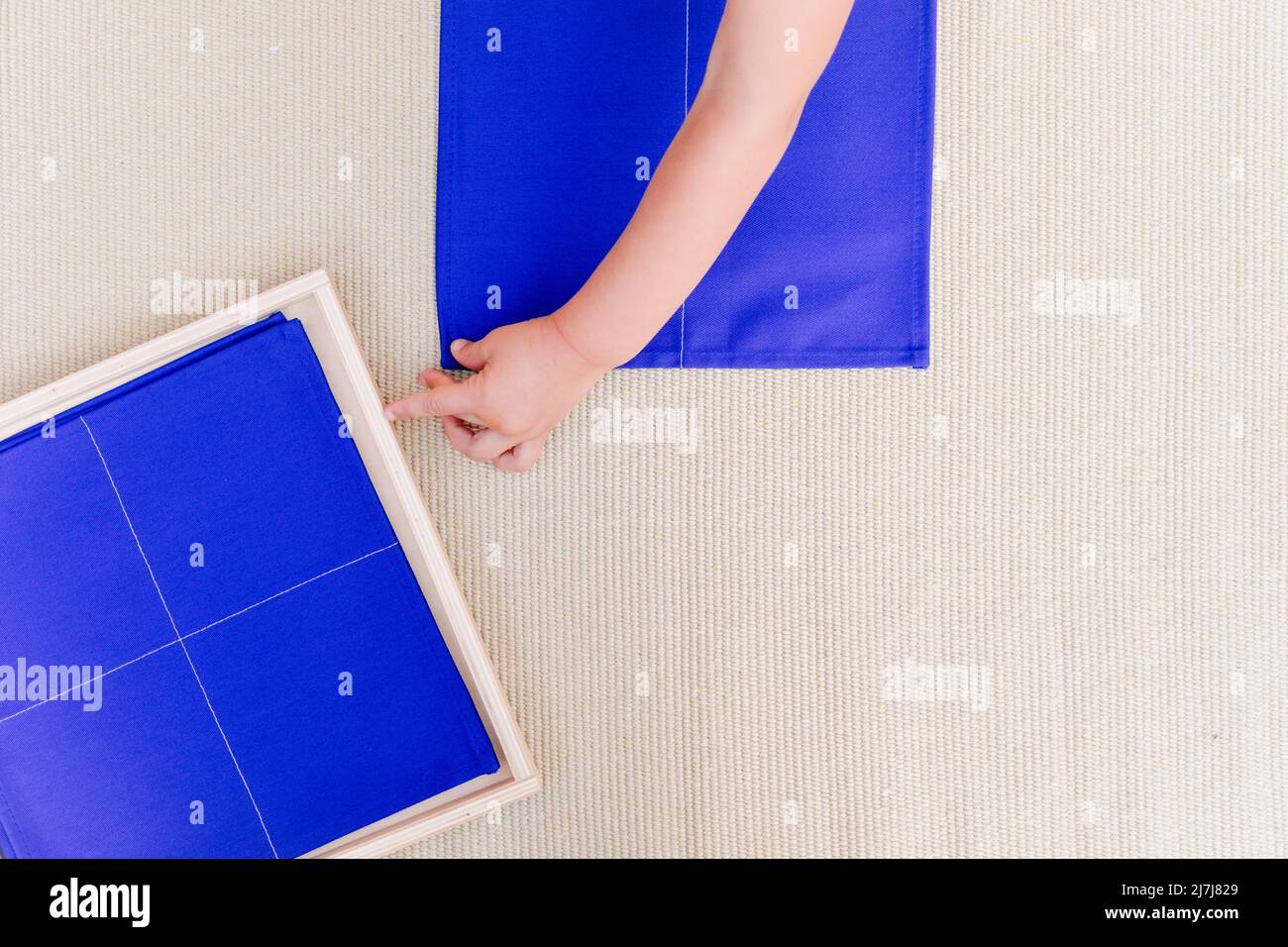 Hände eines Mädchens in einer montessori-Schule im Bereich des täglichen Lebens, Falten einer Serviette. Stockfoto