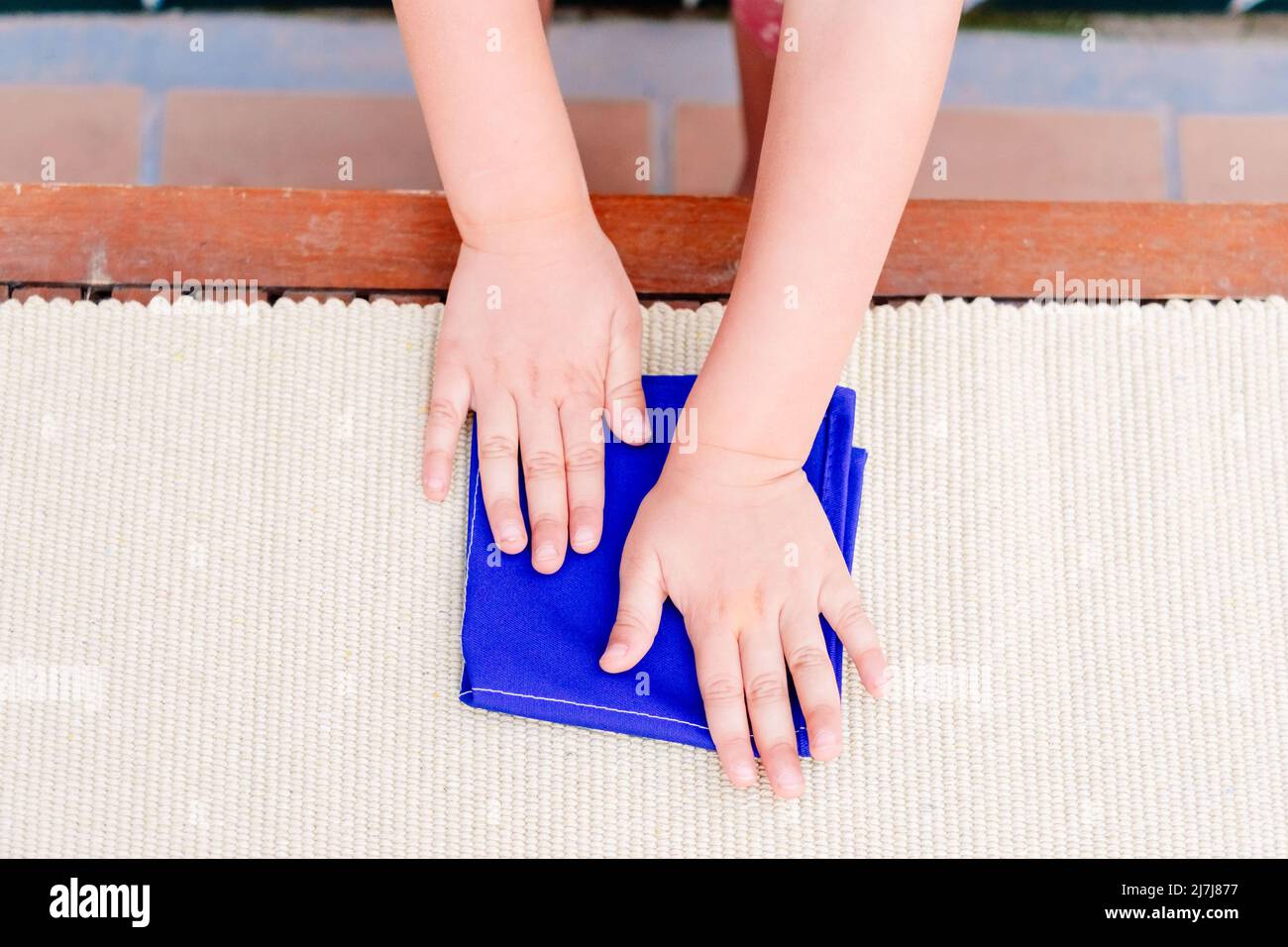 Hände eines Mädchens in einer montessori-Schule im Bereich des täglichen Lebens, Falten einer Serviette. Stockfoto