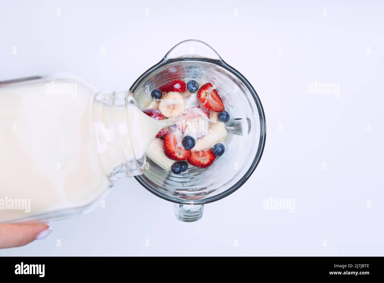 Smoothie oder Milchshake im Mixer zubereiten. Milch in einen Mixer mit Früchten gießen. Veganer Smoothie mit pflanzlicher Milch Stockfoto